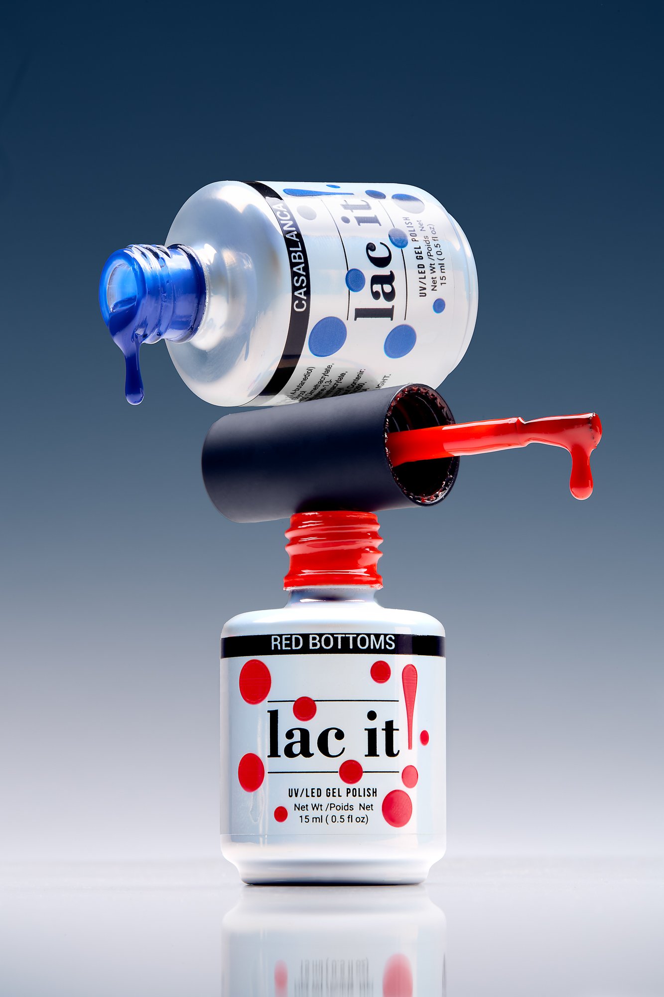 Colorful bottles of nail polish, one blue and one red, with the caps removed and the polish spilling out.