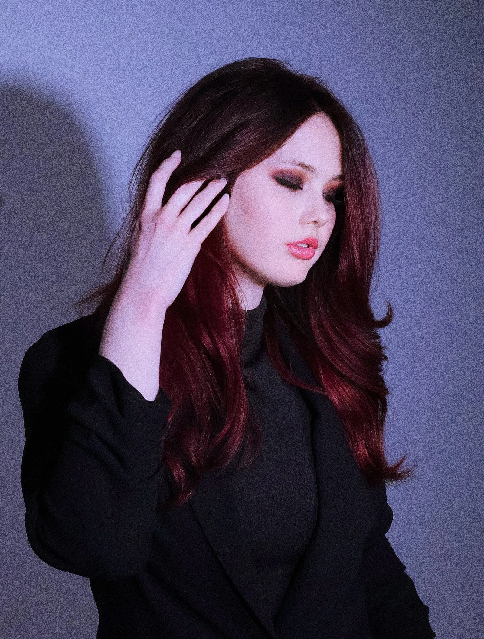 A woman with long, dark red hair. Scarlett Siren Service. All-over double pigmented red hair color. Soft face framing and long layers.