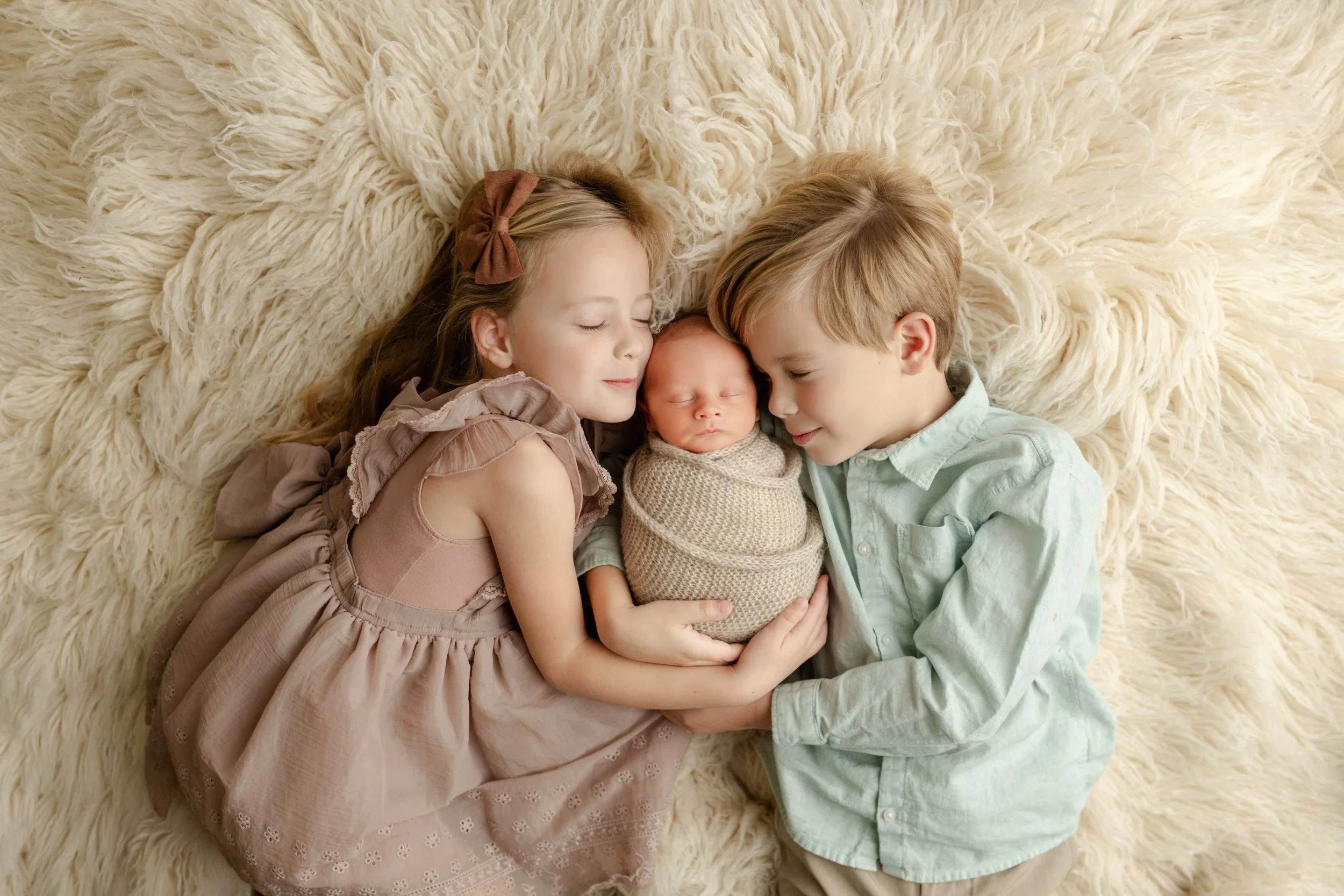 siblings kissing and loving baby in photography studio birmingham al
