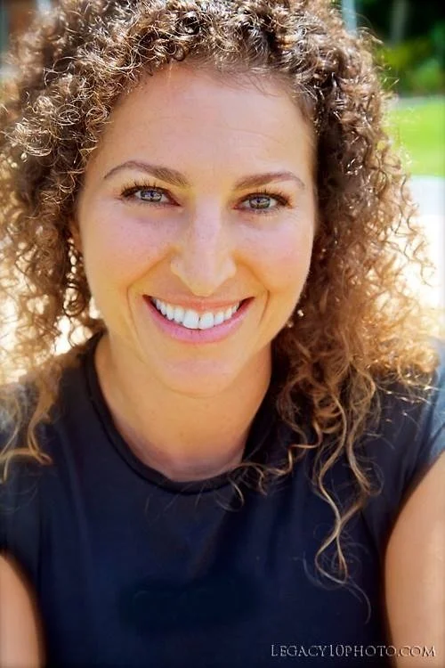 Close-up of a woman with curly hair smiling outdoors