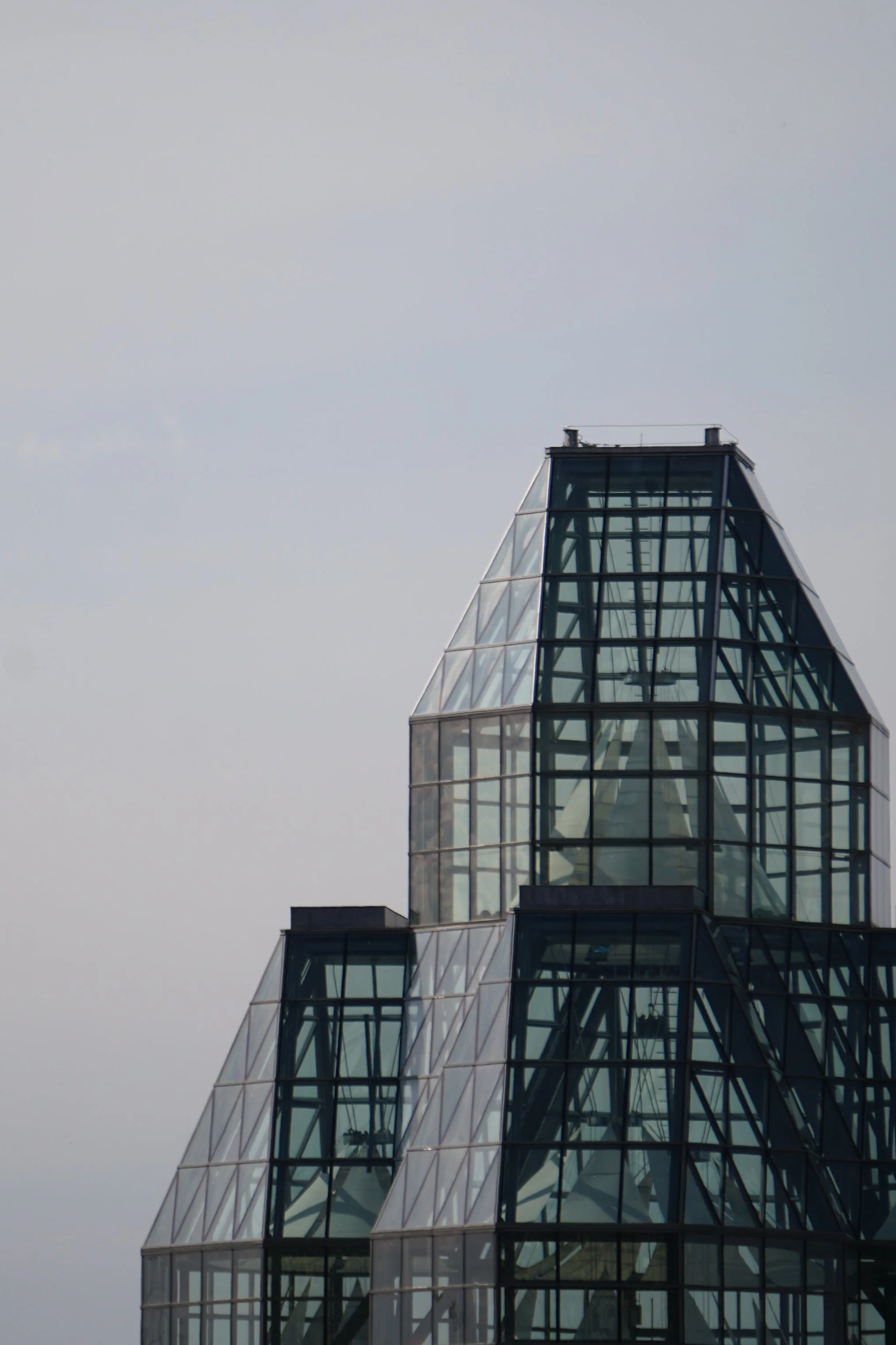 Close-up of a modern glass skyscraper with multiple angled and rectangular glass sections.