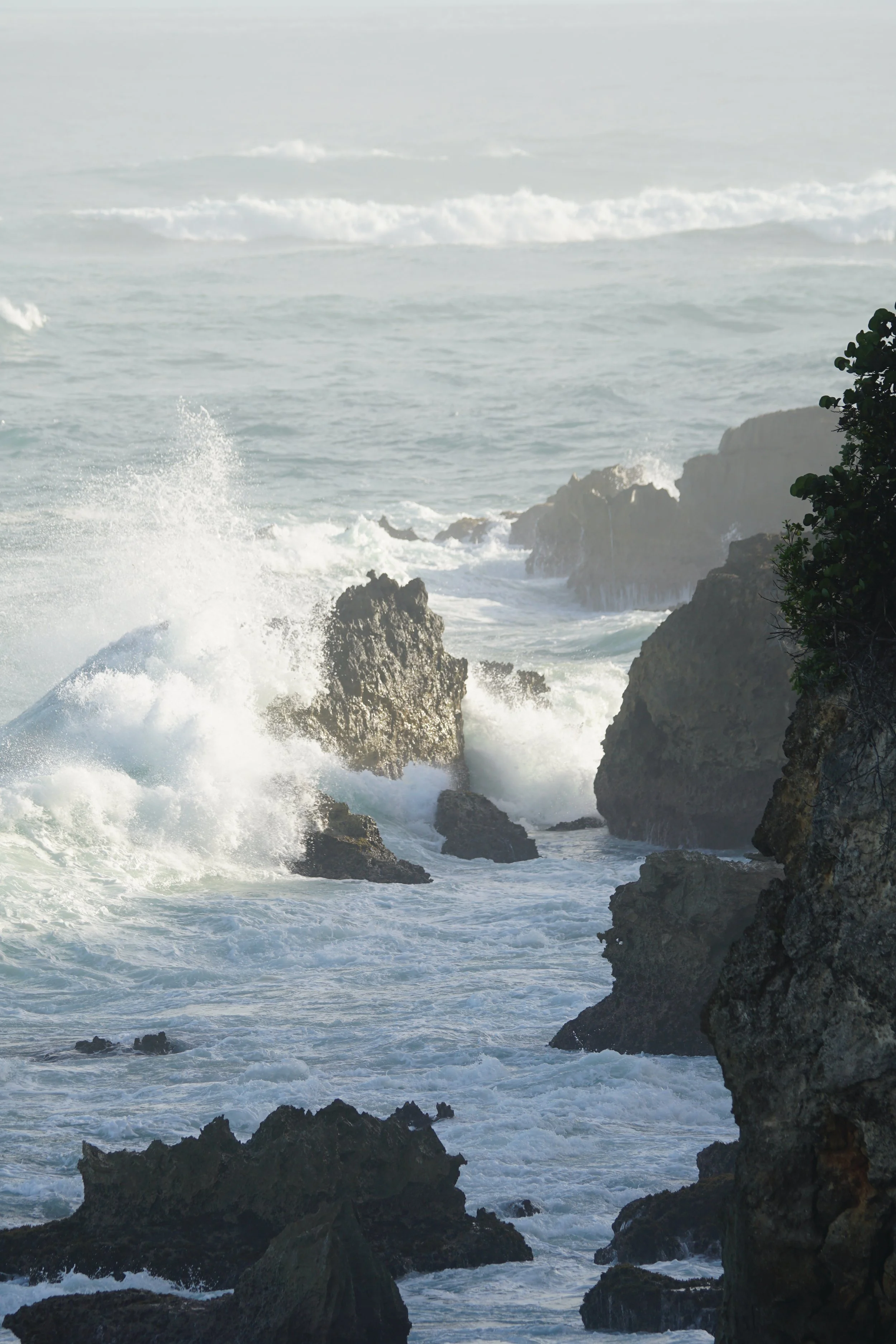 Waves crashing against rocky coastline with ocean in the background.