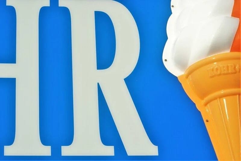 Close-up of large white letters 'HR' against a blue background, partially showing an ice cream cone decoration on the right.