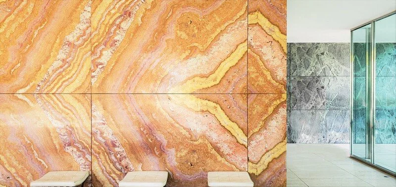 Interior space with a large wall made of colorful, patterned stone tiles, and glass doors leading outside.