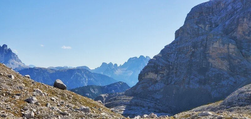 Mountain landscape with rocky terrain and large cliffs under a clear blue sky.