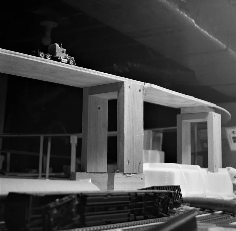 Children's wooden train set on a table with toy trains and tracks in black and white.
