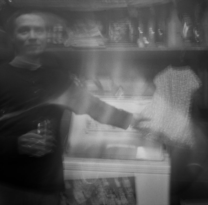 A person handing over a gift bag to another person in an indoor setting, possibly a store.