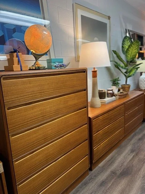 Mid-century modern wooden sideboard with a globe, a desk lamp, and decorative plants and bowls on top.
