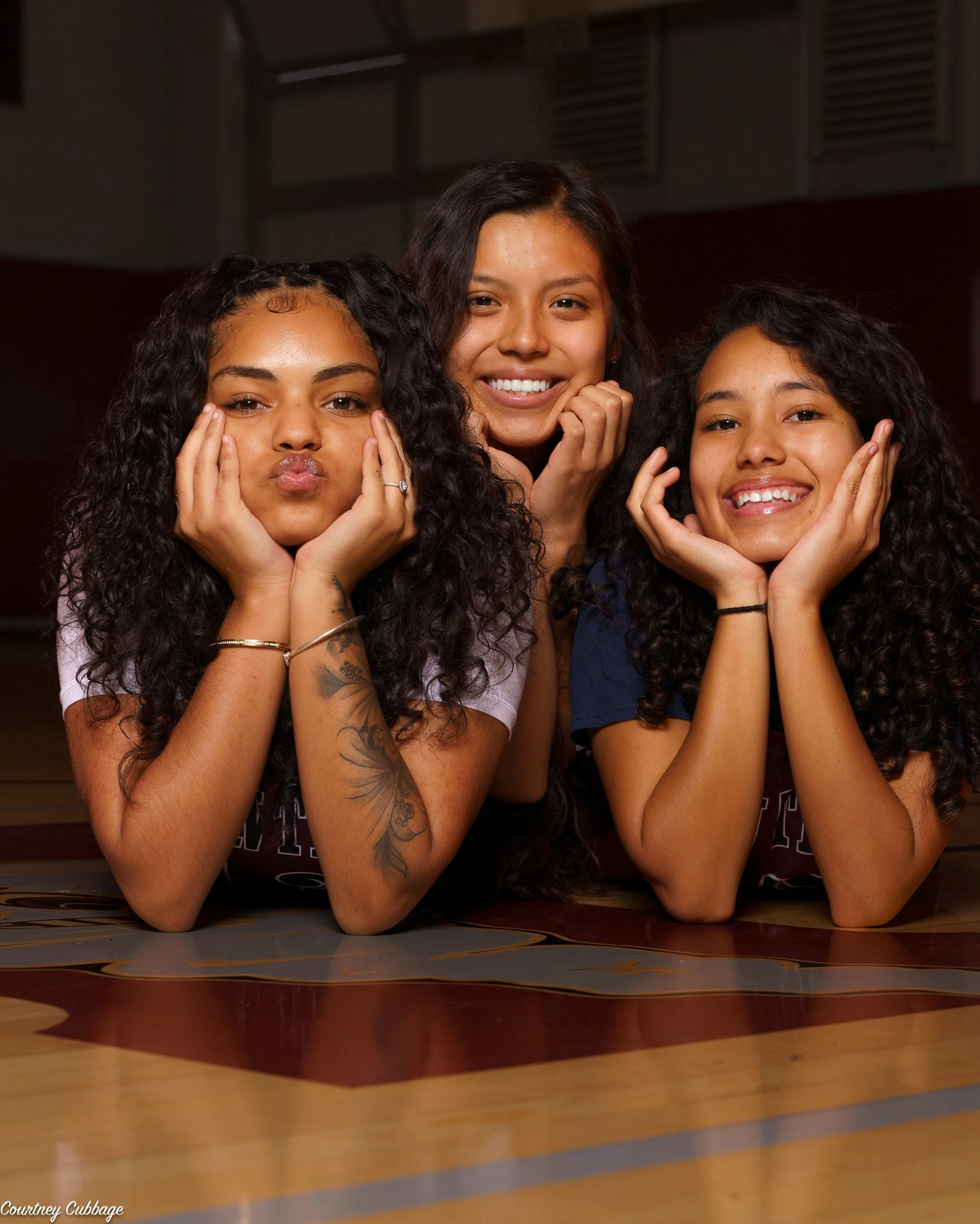 Three high school basketball teammates posing together on the court during a media day