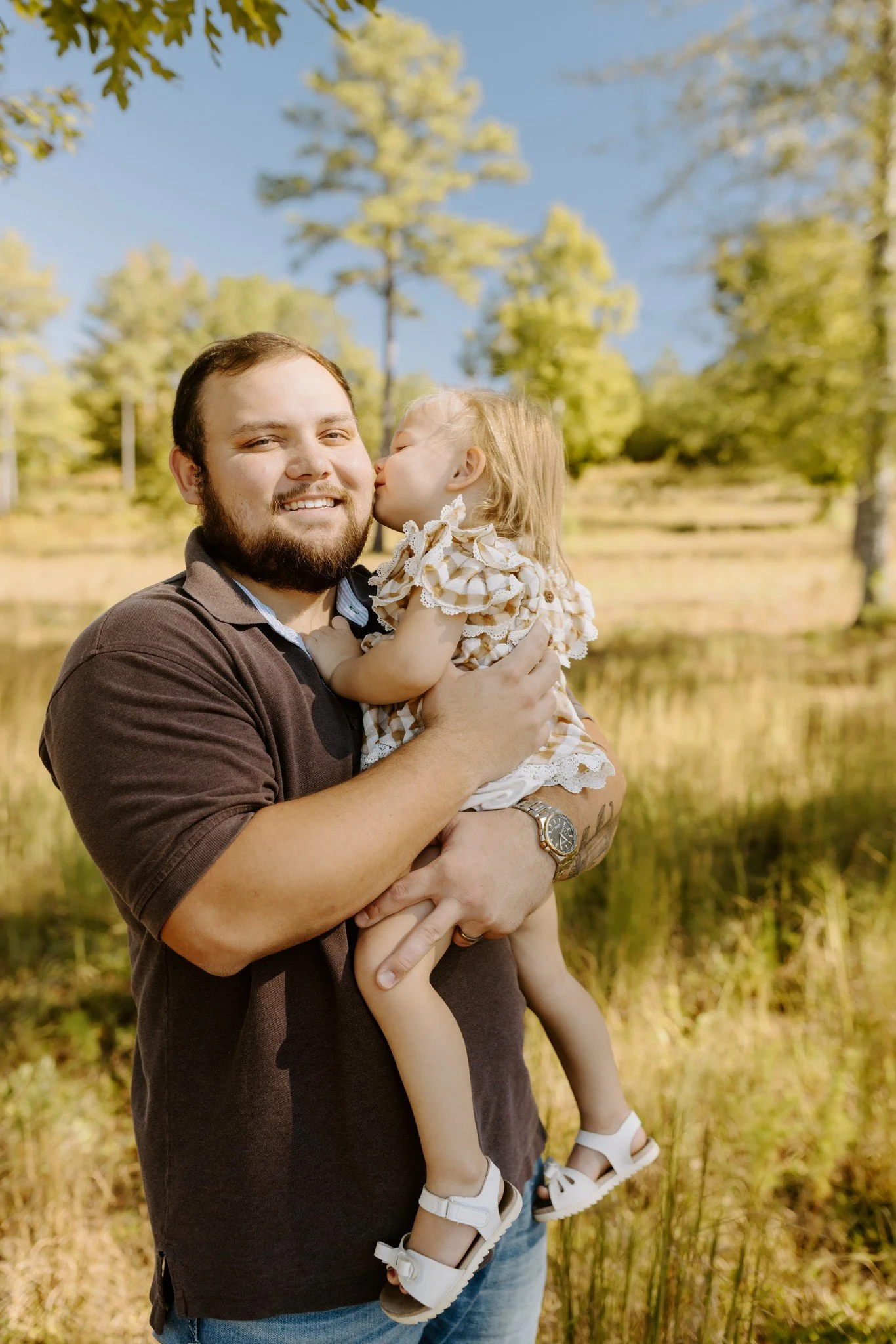 Dad laughs as his little girl kisses him on the cheek during fall family photos