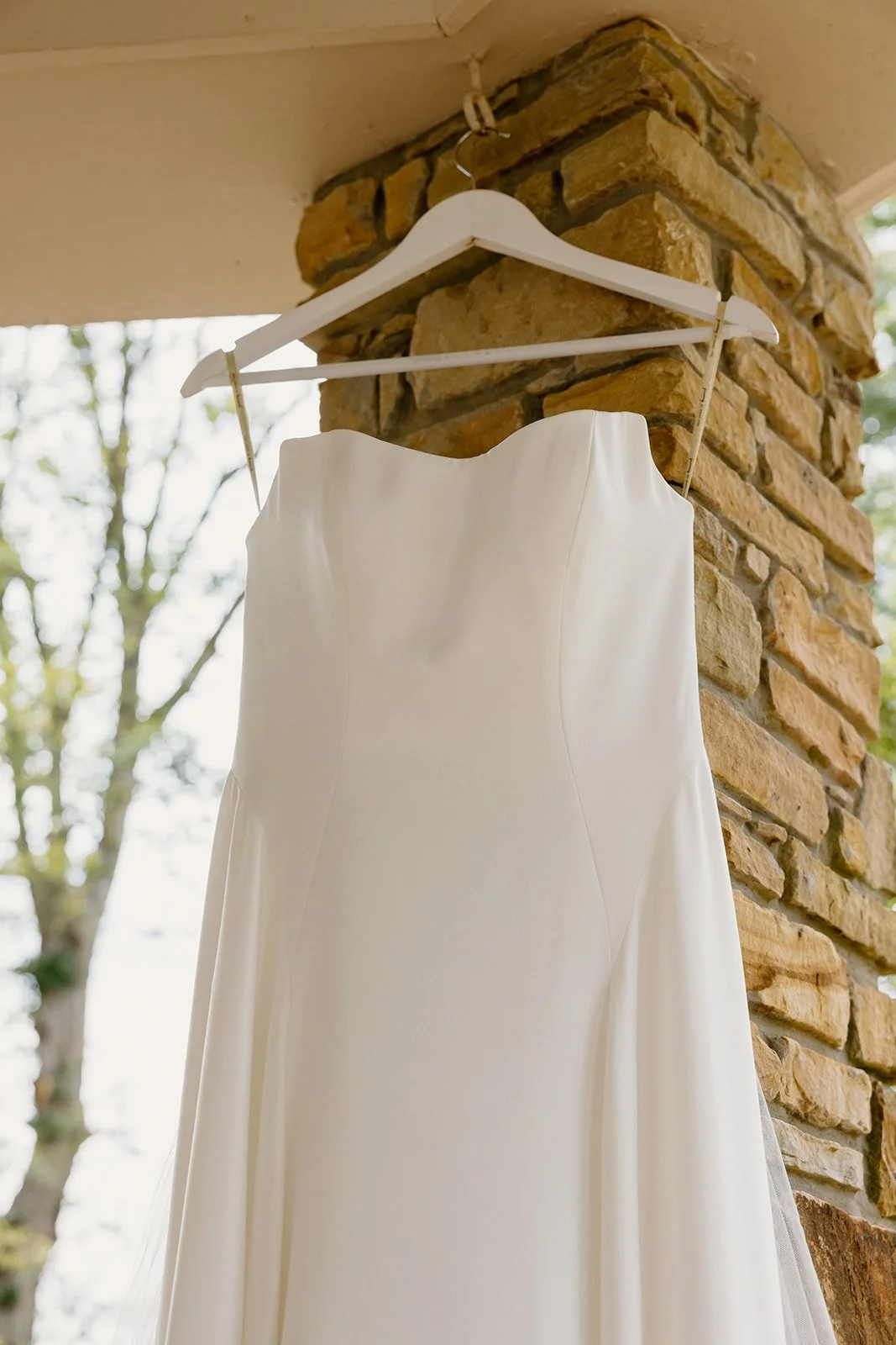 Wedding dress hanging on a wooden hanger at Burritt on the Mountain