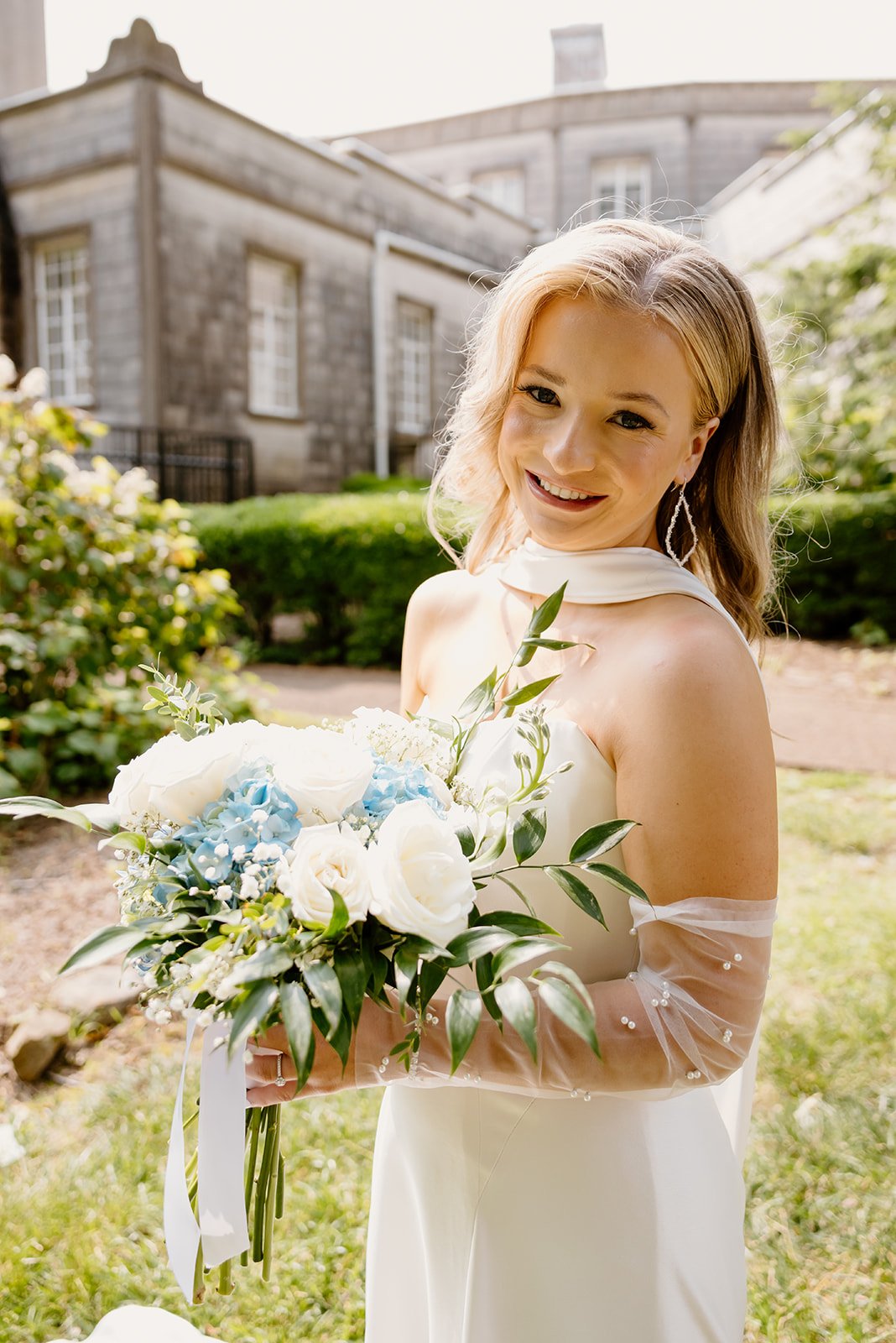Bride holding her white bouquet by the historic mansion at Burritt on the Mountain