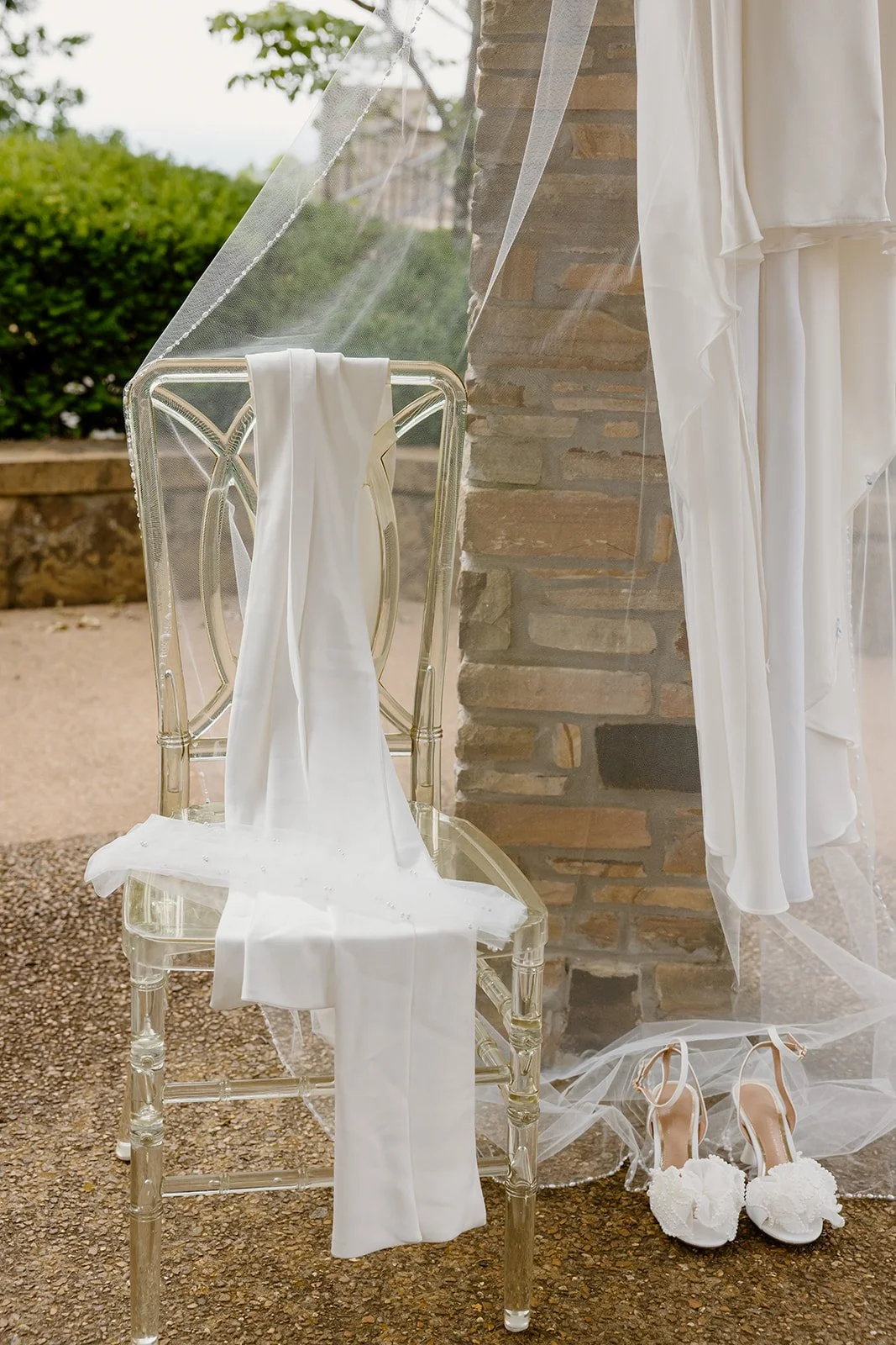 Wedding dress and bridal shoes on a clear chair at Burritt on the Mountain
