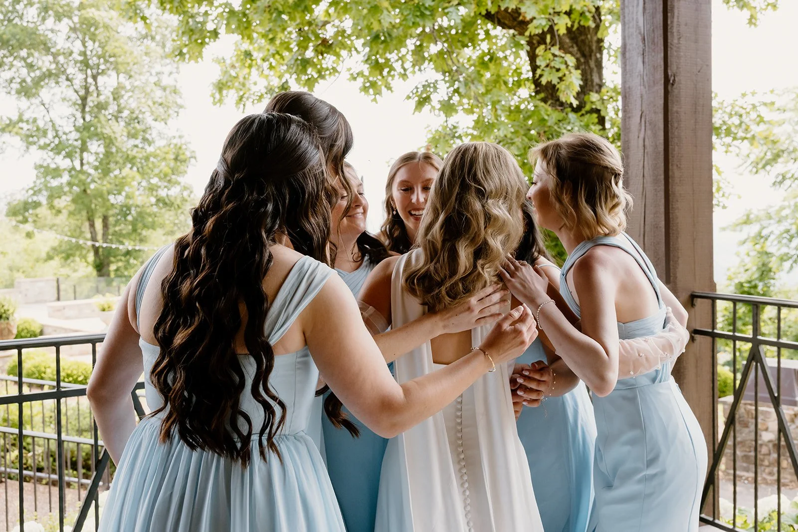 Bride and bridesmaids sharing a hug after their first look
