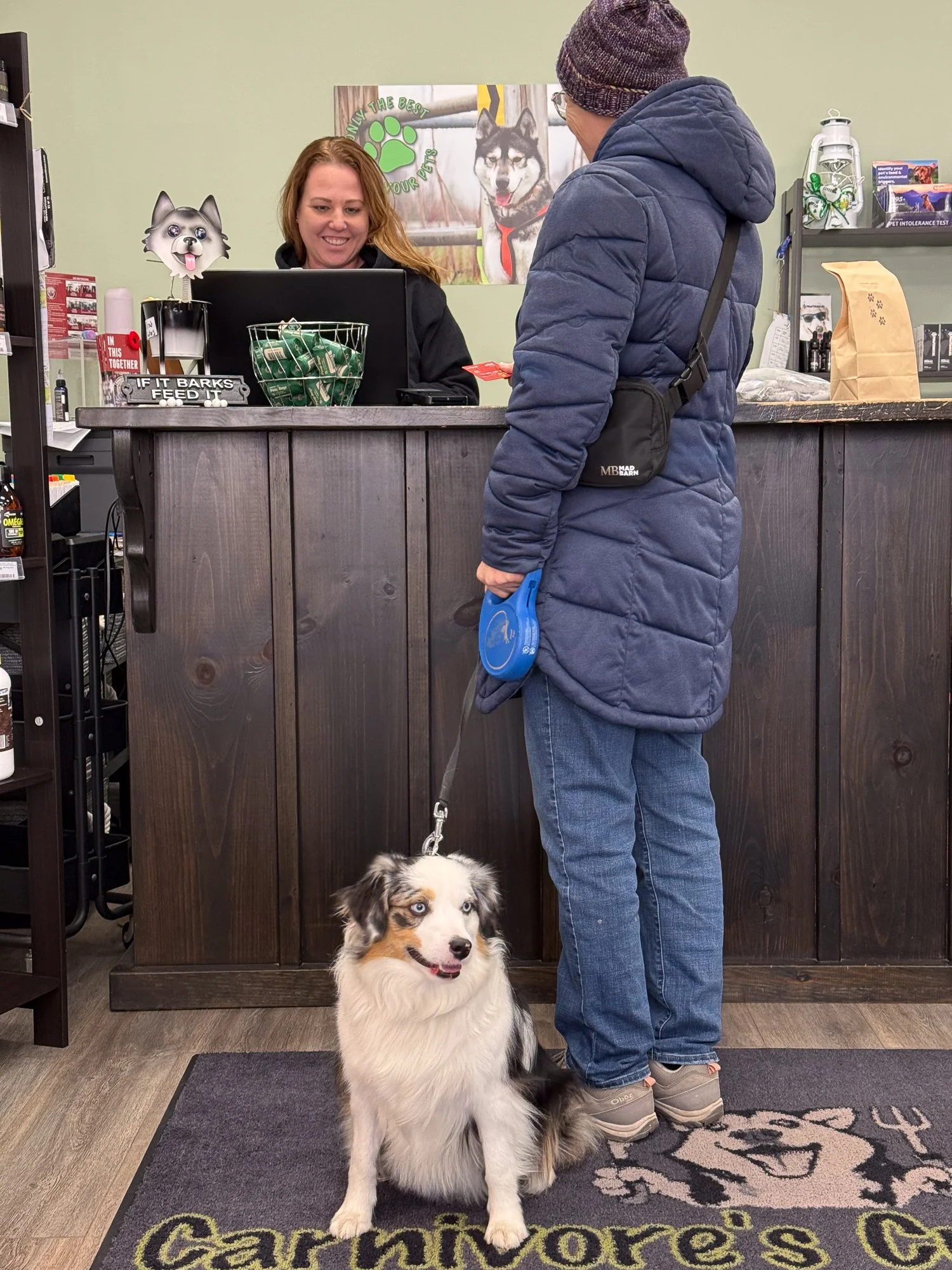 a picture of a staff member helping a client and her dog at the counter.