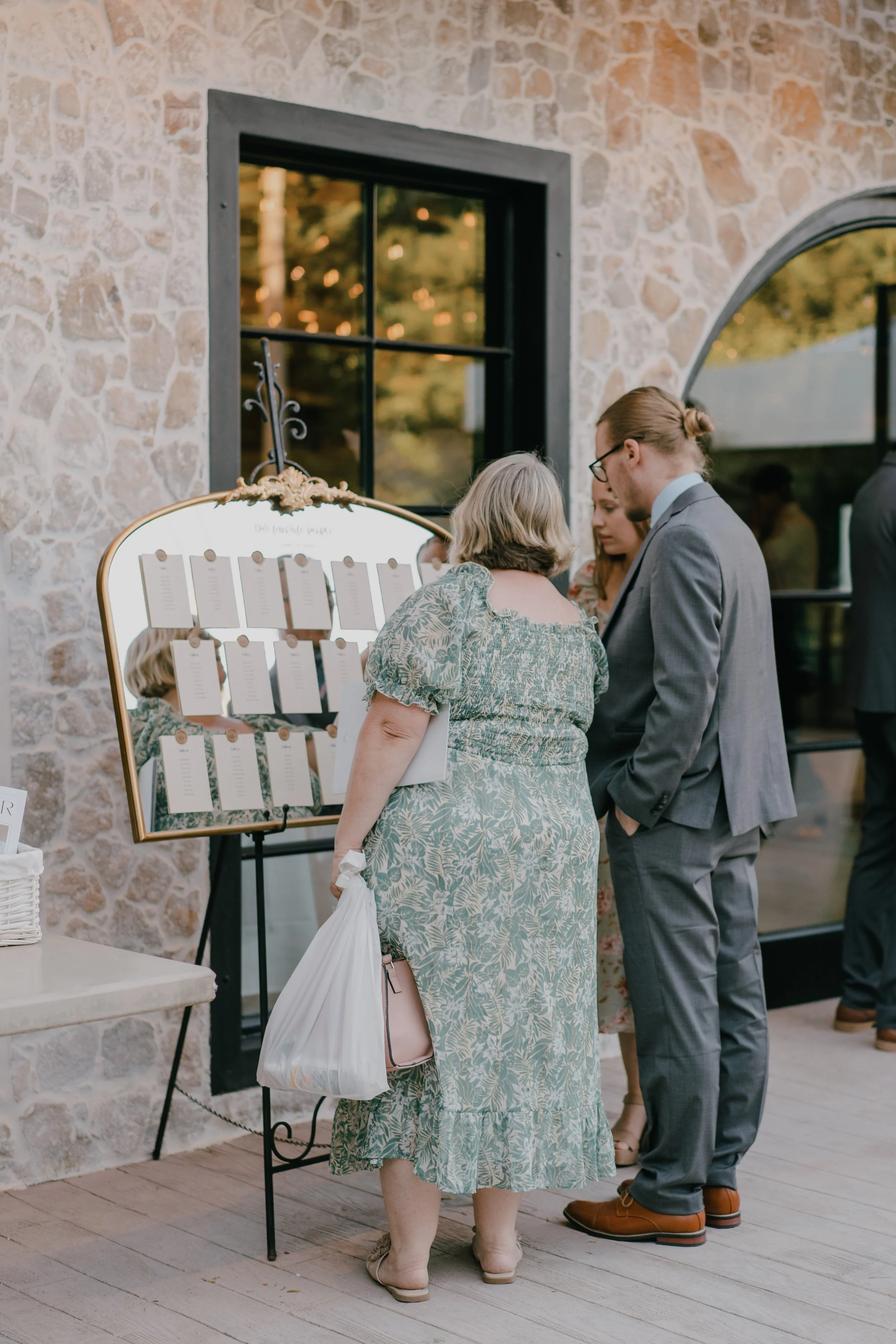 Group of people looking at a seating chart on a wall at a wedding or event venue.