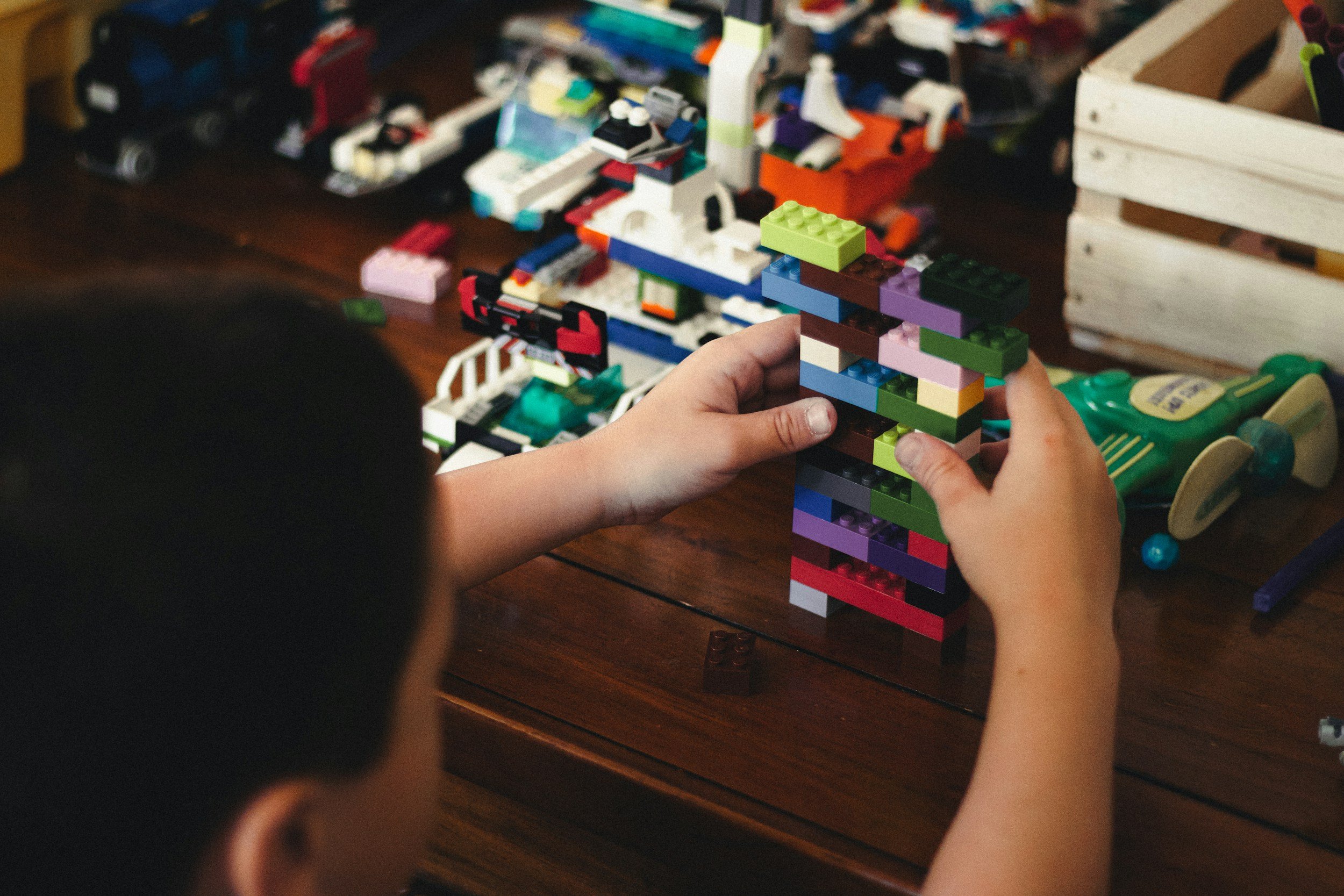 Kind spielt mit bunten Legosteinen