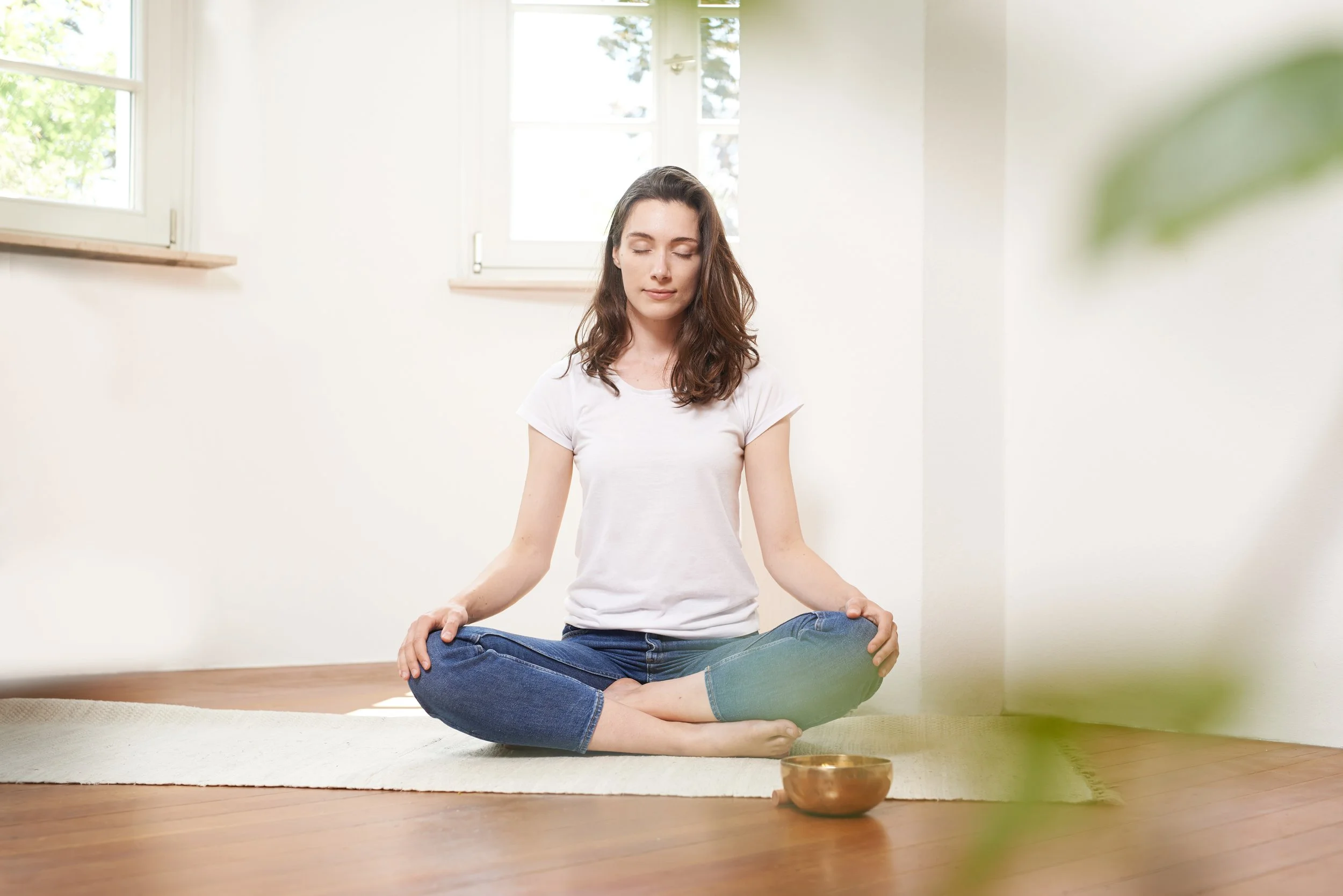 Suzan in Meditationshaltung mit geschlossenen Augen und einer Klangschale vor sich.