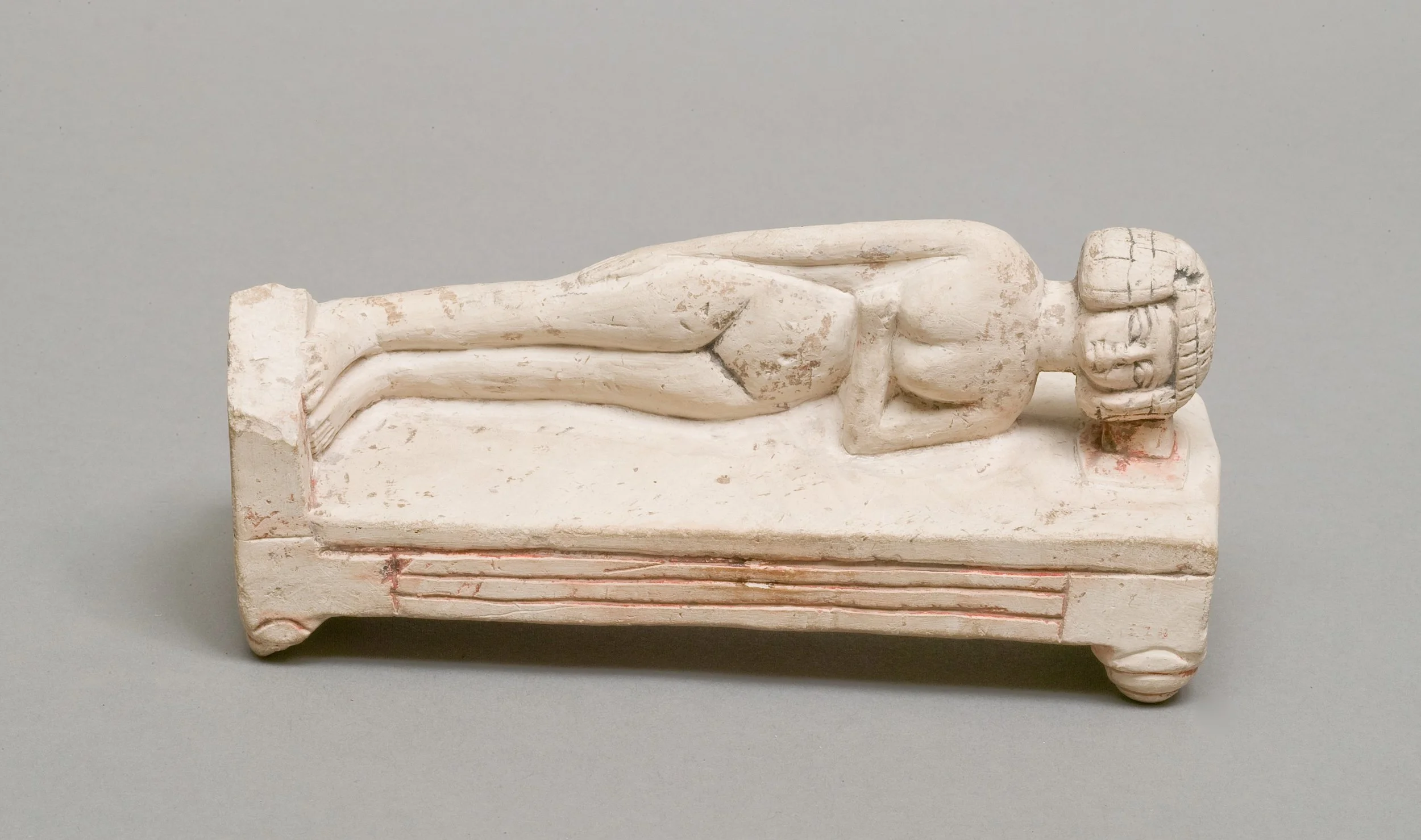 Steinfigur liegend auf einem Bett.