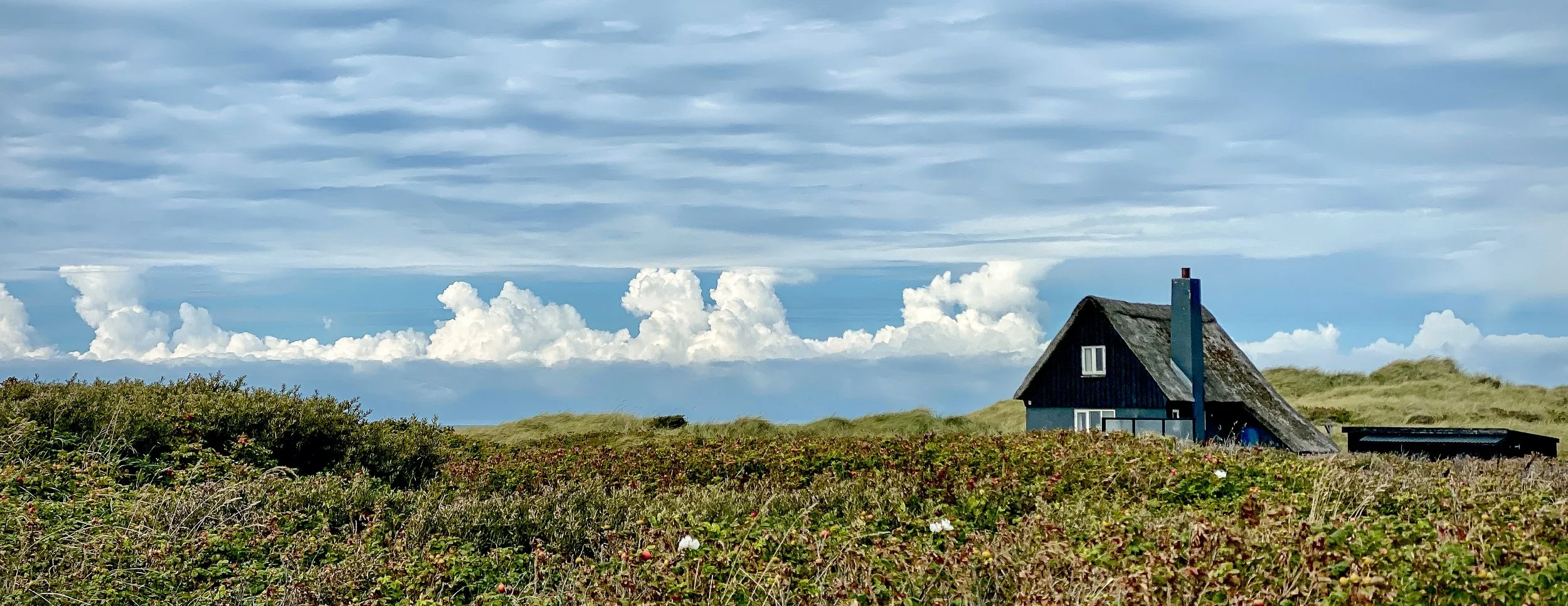dänisches Reetdachhaus, blauer Himmel, Wolken und Dünen