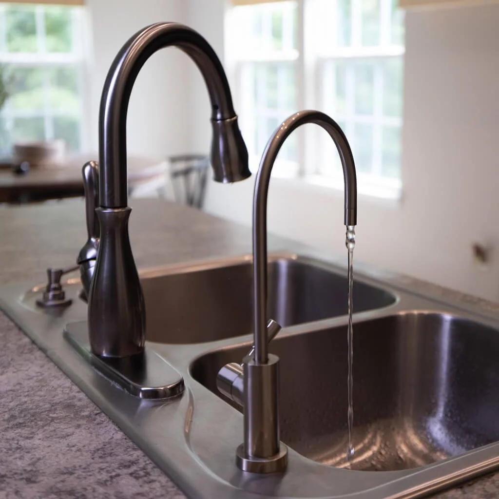Kitchen faucet with water running into a double sink.