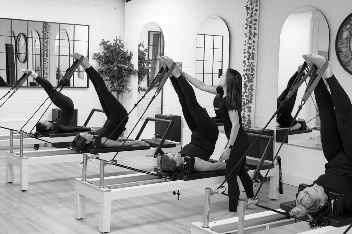Pilates instructor working with a client on a reformer during a wellness brand photography session