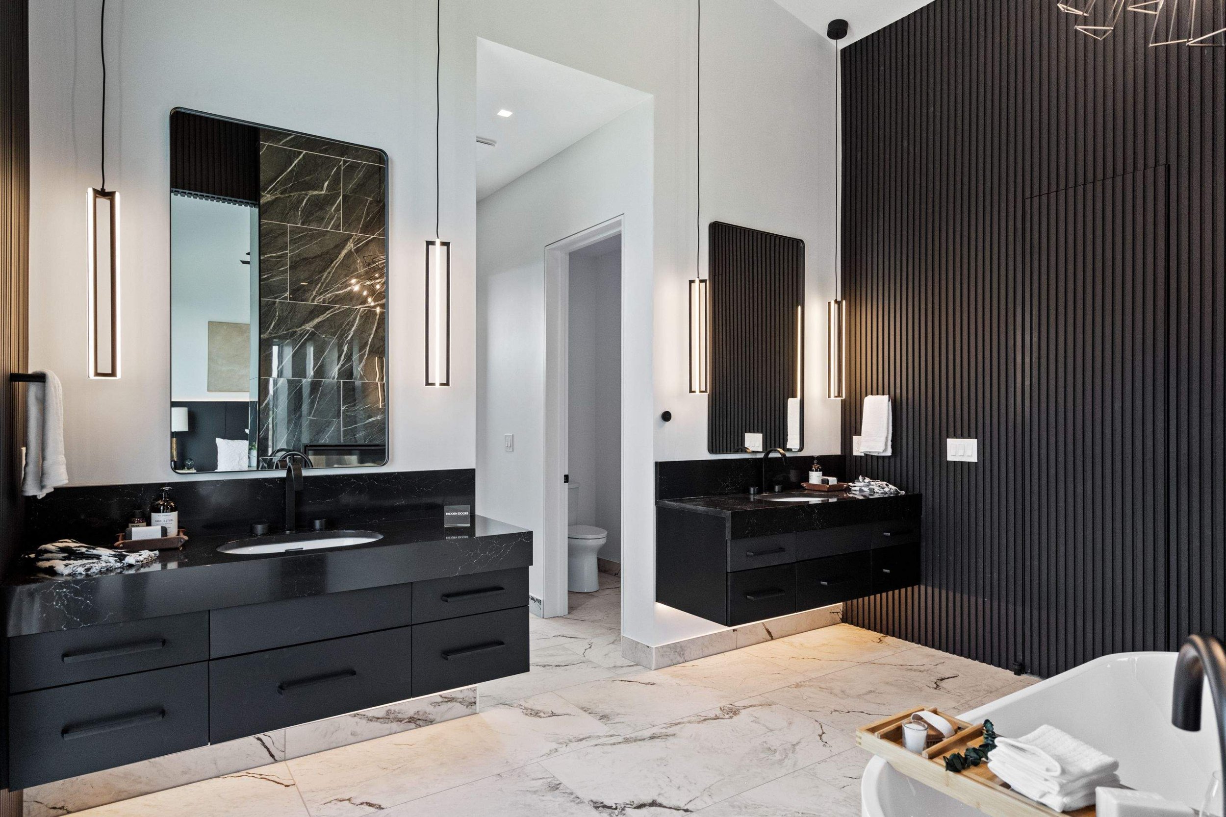 This sophisticated bathroom features vertical pendant lights framing the mirrors, delivering even, glare-free illumination ideal for grooming and everyday use. The integrated under-cabinet lighting enhances the floating vanity design, adding a subtle
