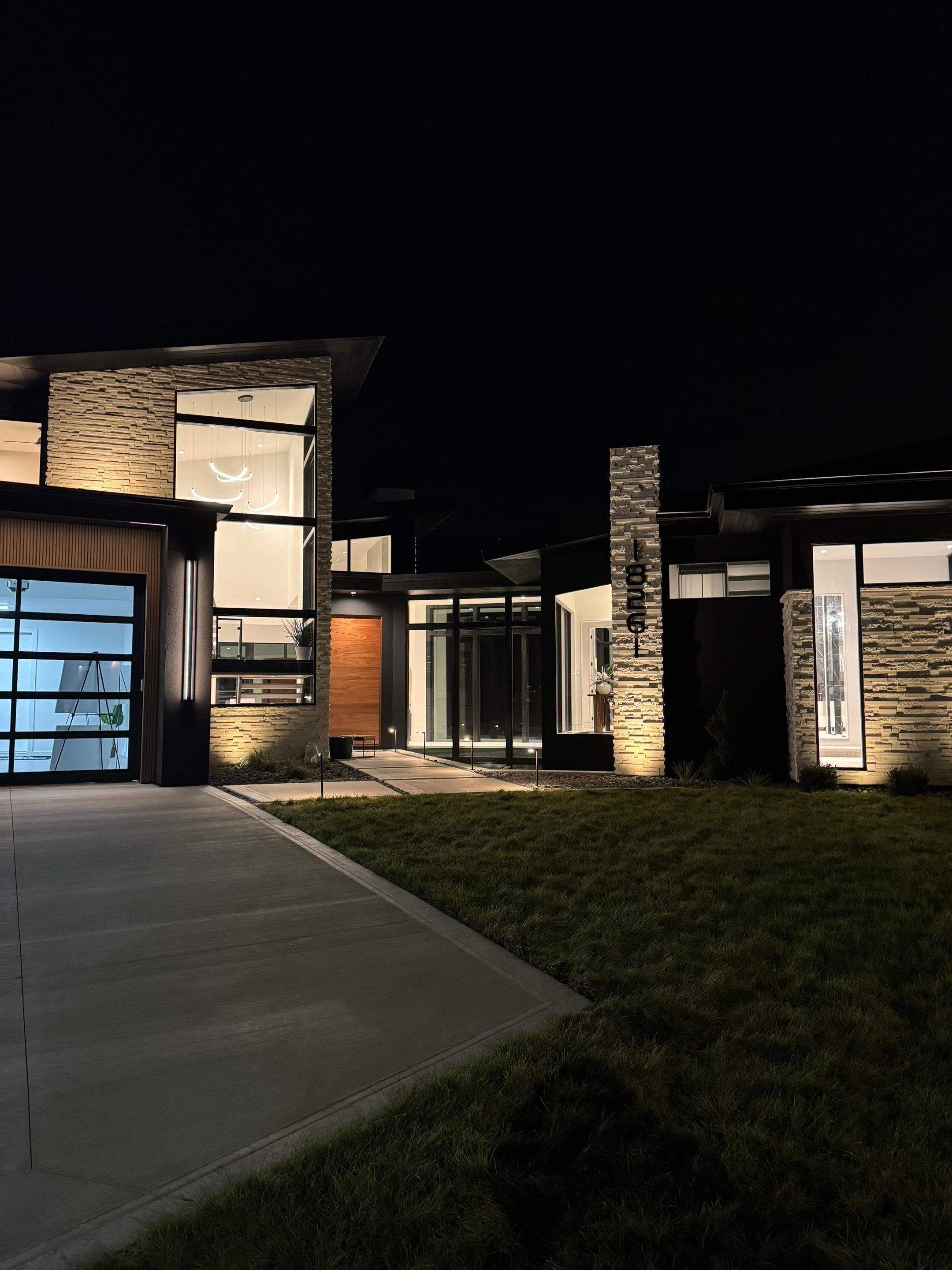 The home’s exterior is transformed at night with precision architectural lighting, showcasing the modern design elements and stone textures with a striking, energy-efficient glow.