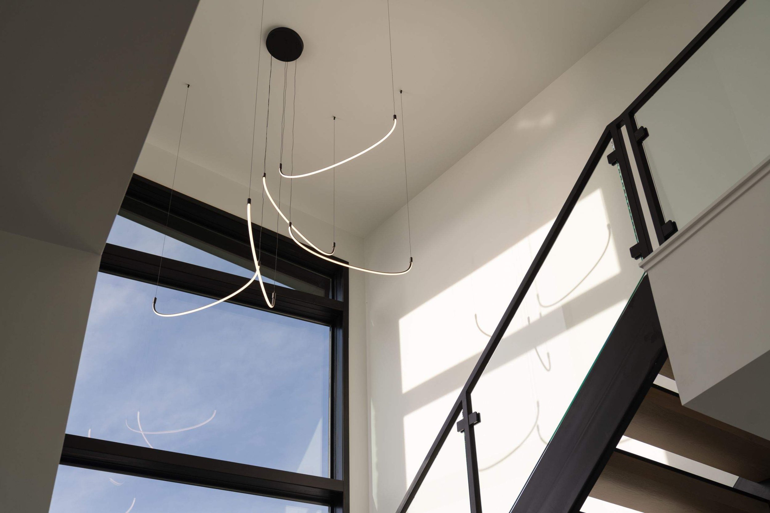 A visually captivating staircase featuring floating steps and elegant sculptural pendant lighting. The fixtures create a dramatic effect, enhancing the minimalist architecture with soft, ambient light.