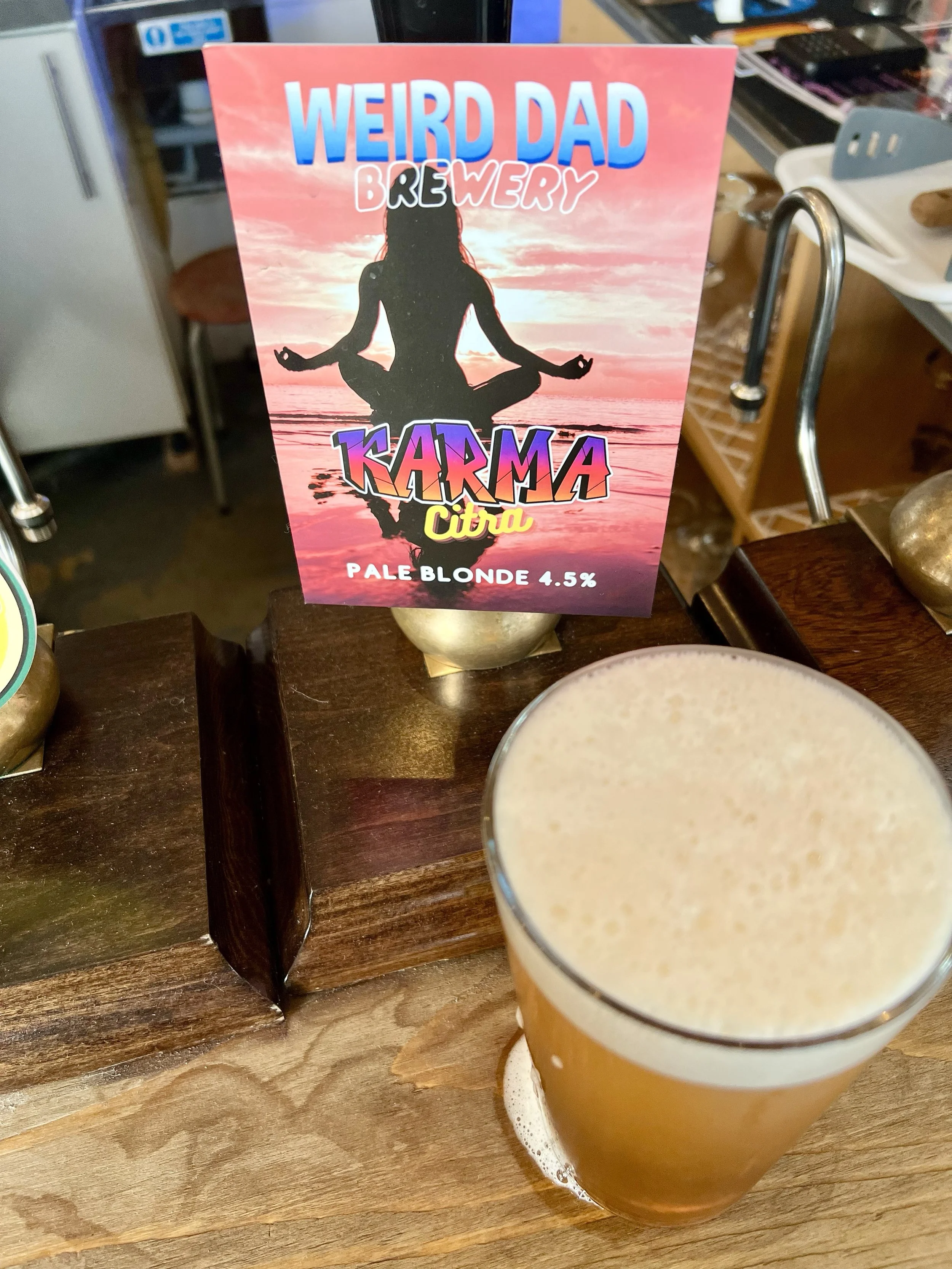 A pulled Pint of Karma Citra from Weird Dad in front of it's Hand Pump and Clip