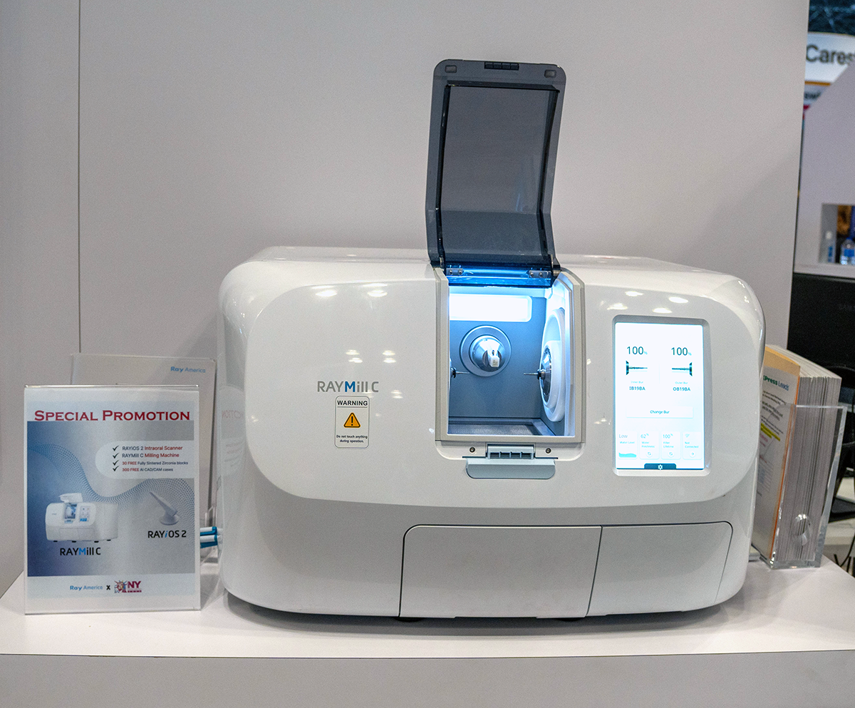 Medical device with a digital display and a compartment, likely a laboratory analyzer, positioned on a white surface with promotional materials nearby.