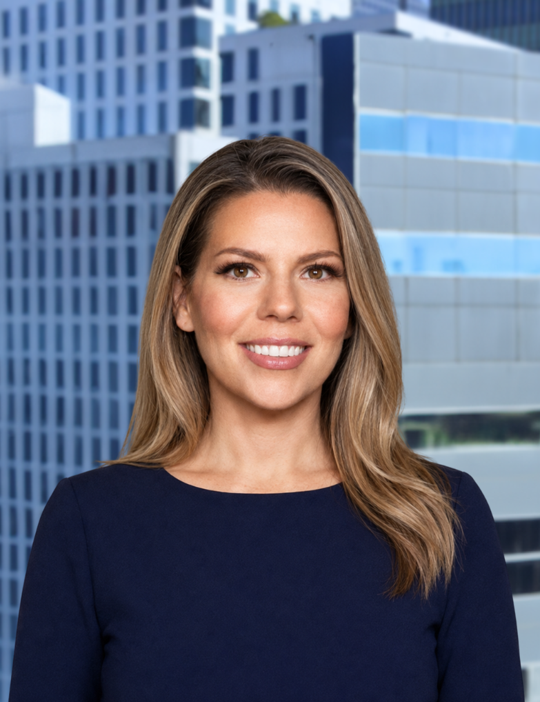 A woman with shoulder-length brown hair, wearing a black top, smiling in front of a cityscape with modern glass buildings.