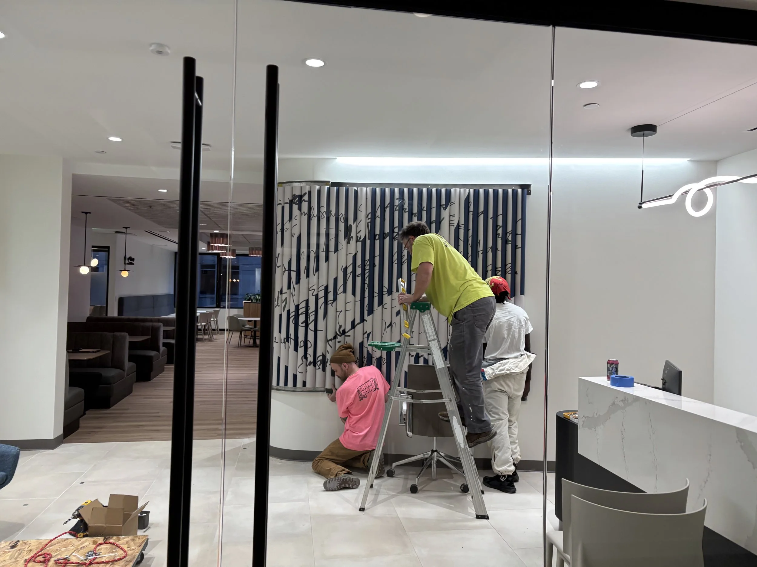 Three men installing a large entryway sign