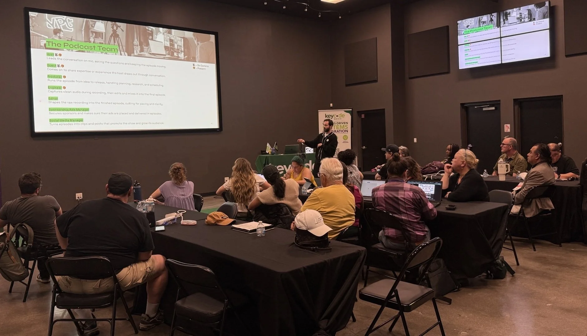 Lawrence Grey presents The Podcast Team roles slide during the Podcasting 101 lecture for teachers at Key Code Media in Burbank