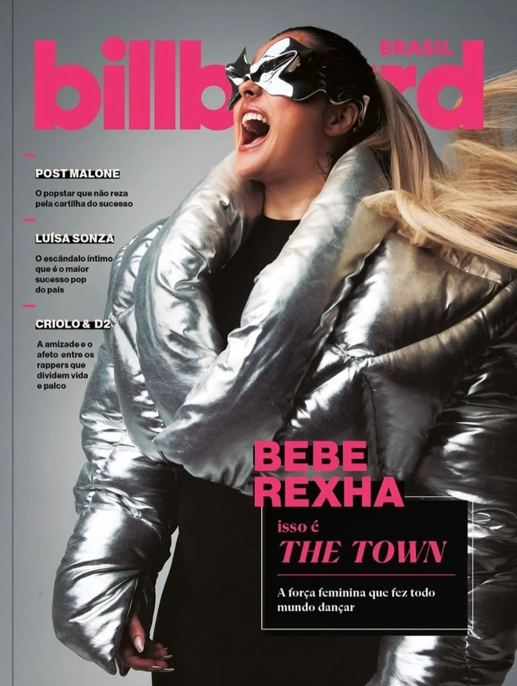 Cover of Billboard Brazil magazine featuring BeBe Rexha wearing reflective silver jacket and futuristic black mask, laughing joyfully.