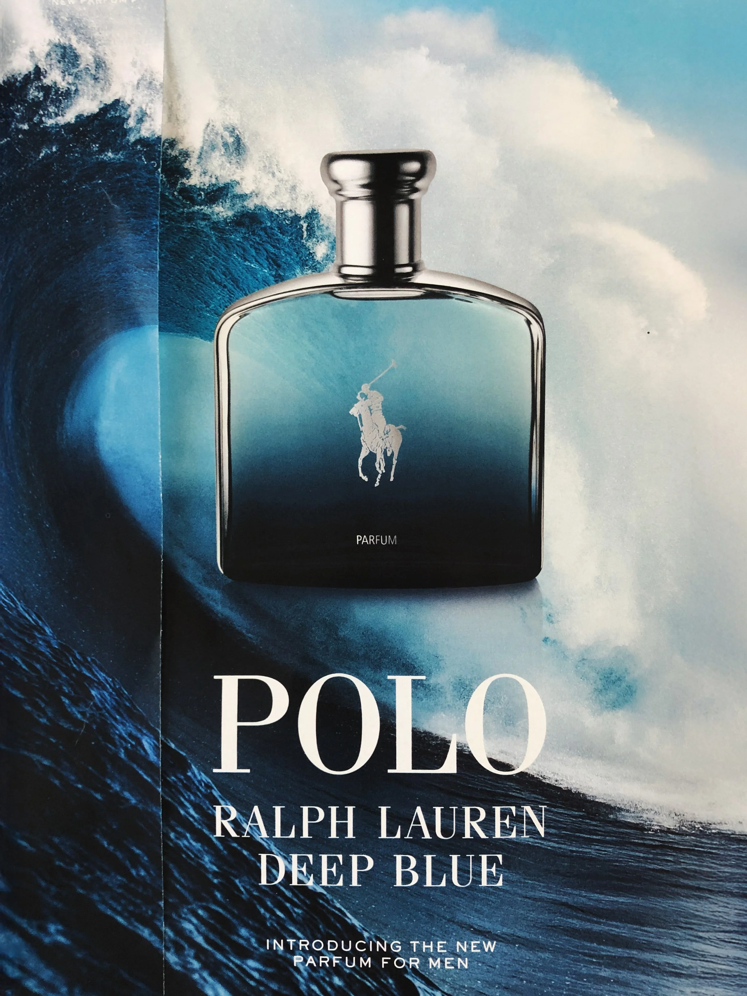 Advertisement for Ralph Lauren Deep Blue men's perfume featuring a black perfume bottle with a polo player silhouette and a background of ocean waves.