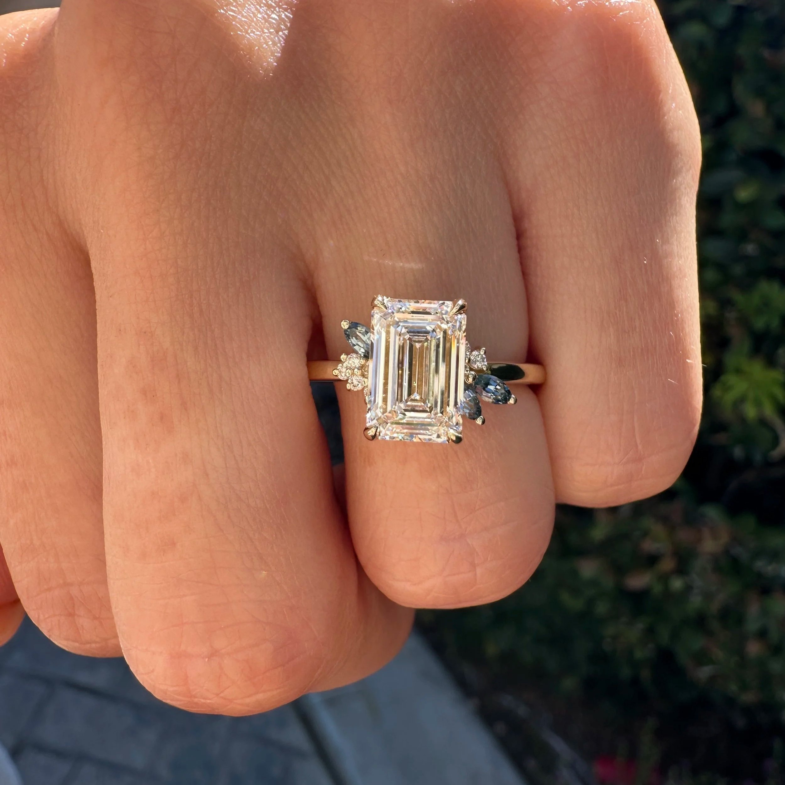 Emerald-cut diamond engagement ring with dark side stones on a yellow gold band