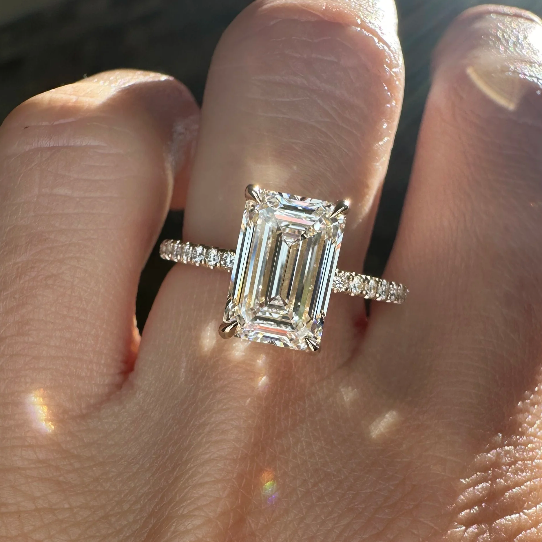 Emerald-cut diamond solitaire engagement ring with a pavé band
