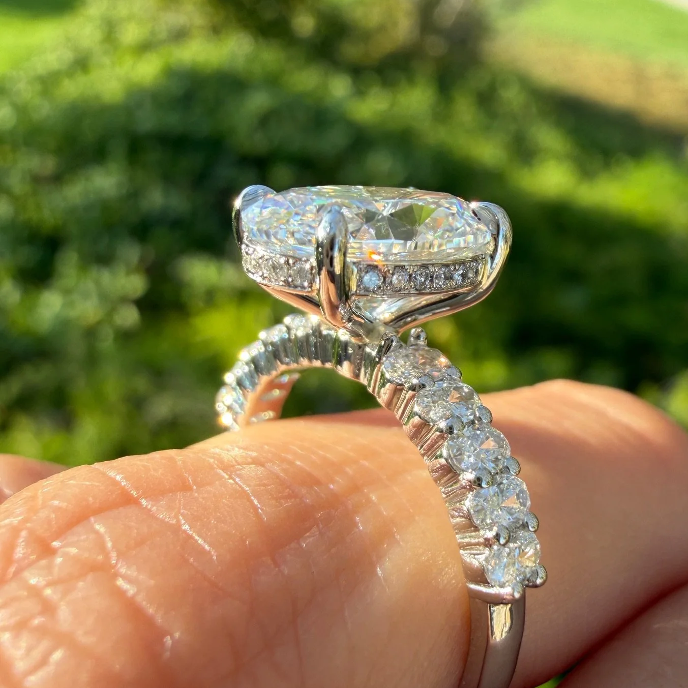 Side view of an oval diamond engagement ring with a hidden halo and diamond band