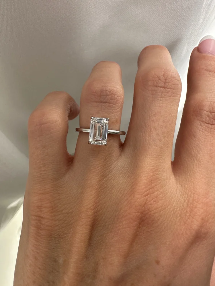 Emerald-cut diamond engagement ring on a hand