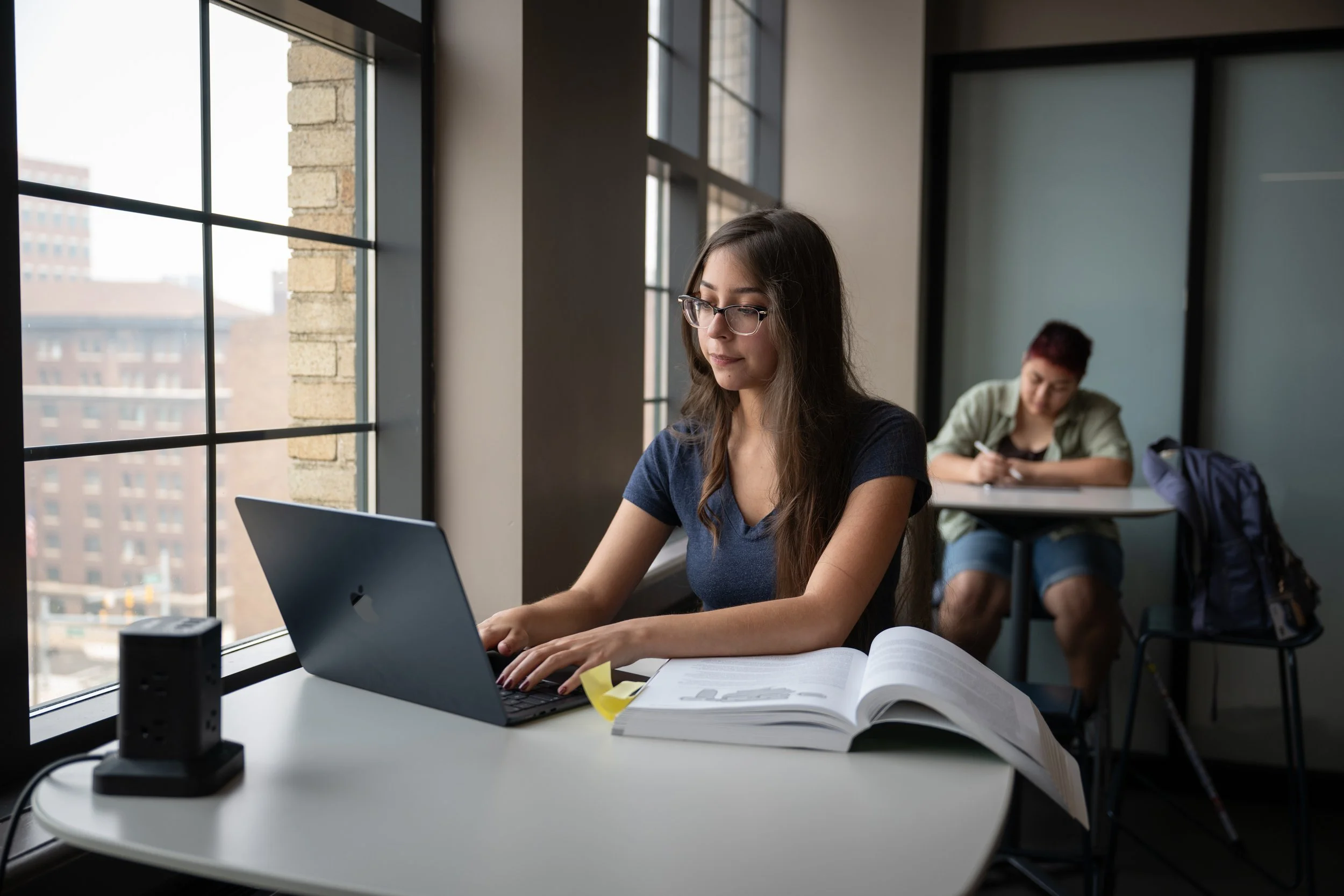 Female sitting typing on her computer by a window
