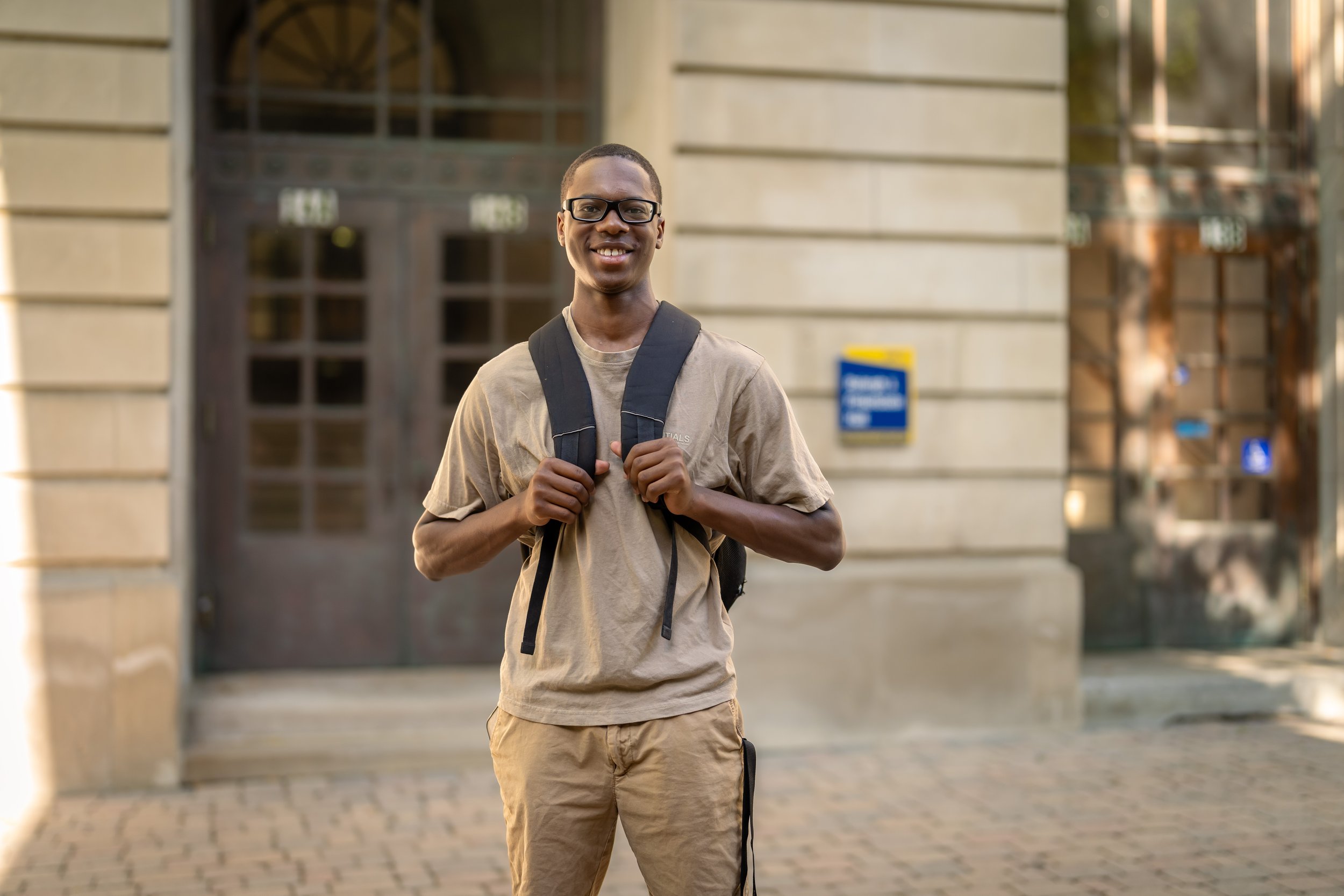 Student standing in front of building wearing a backpack