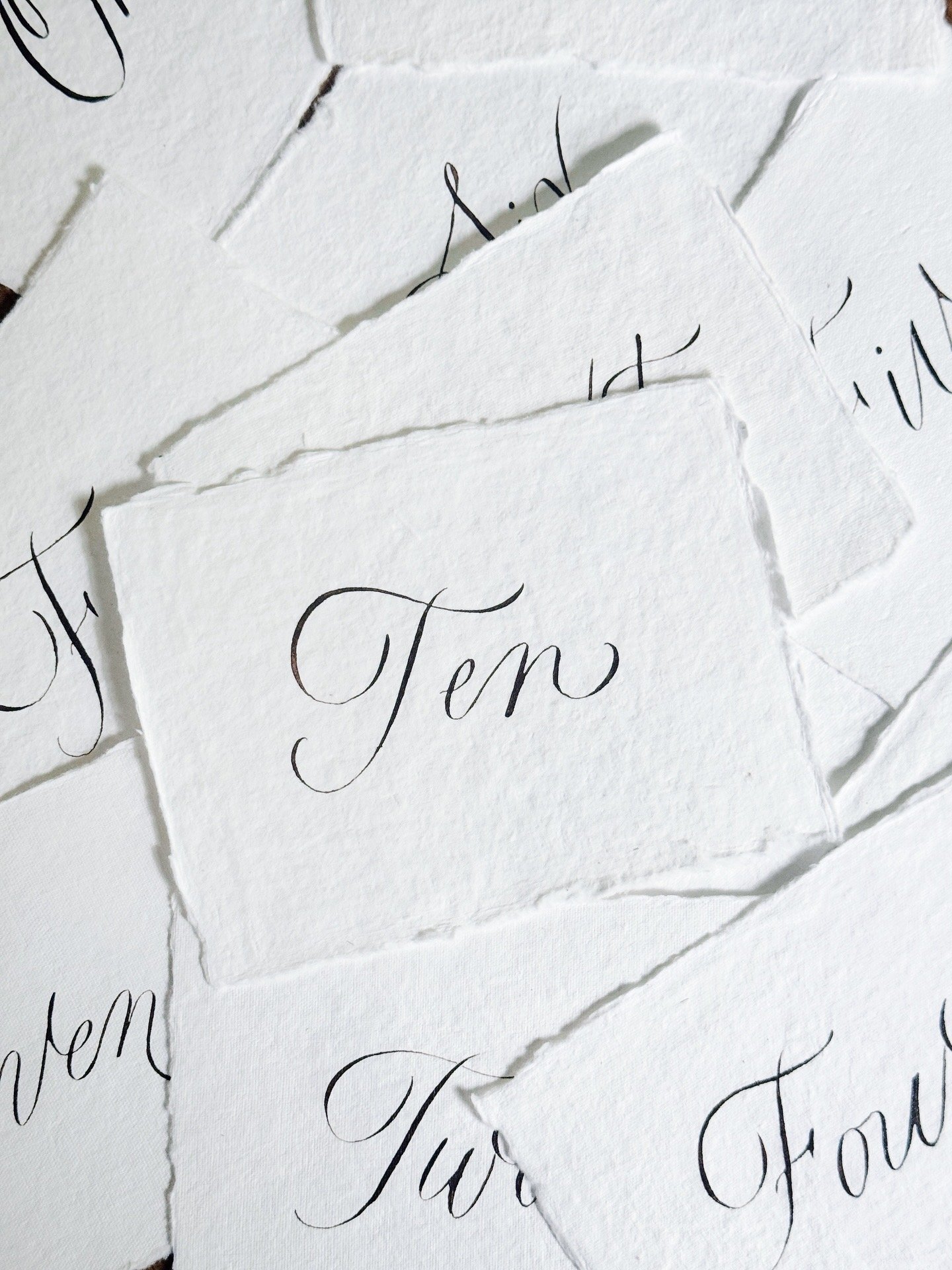 Close-up of torn pieces of white paper with elegant black cursive writing.