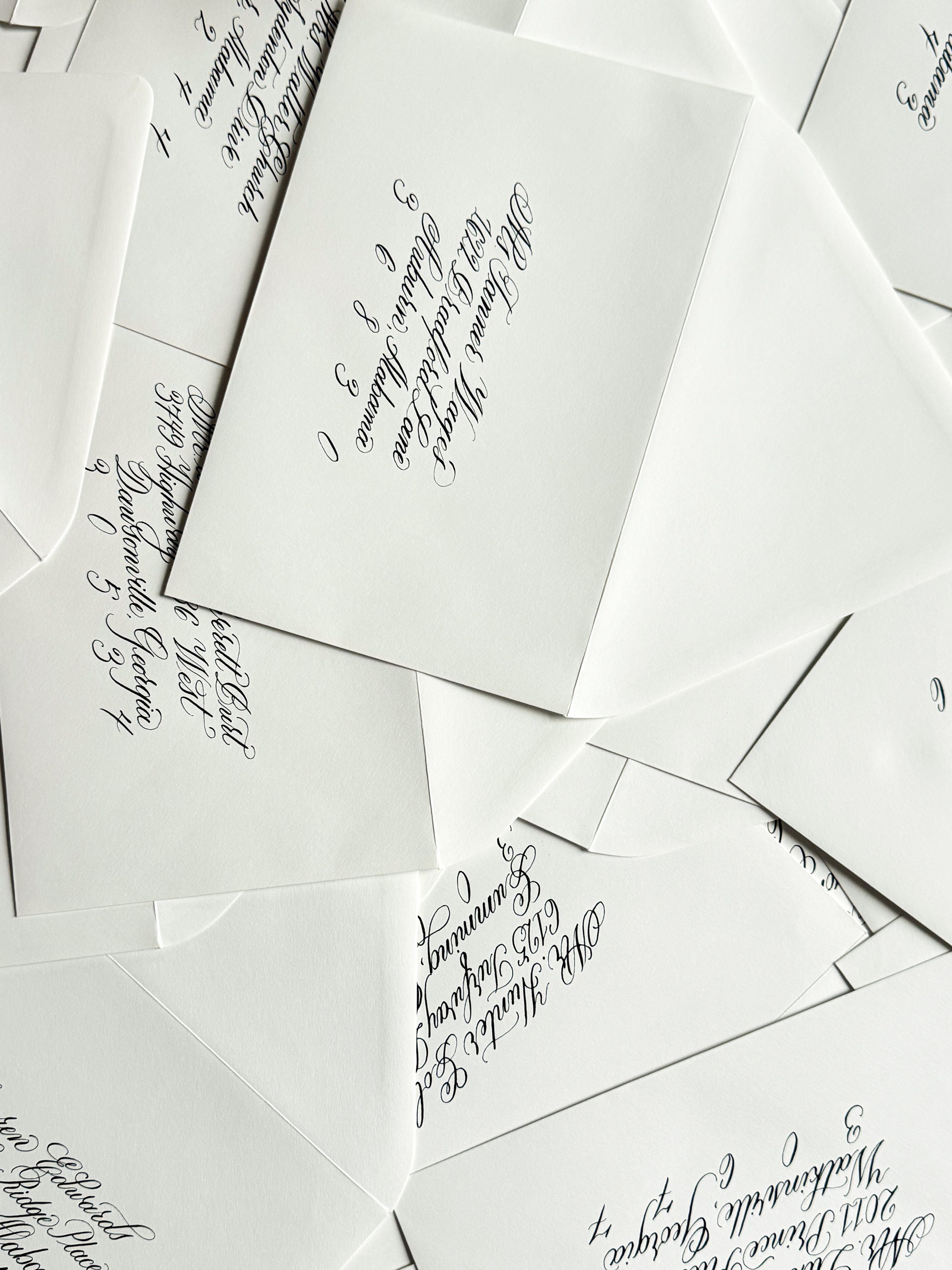 Multiple white envelopes with handwritten calligraphy text on the front.
