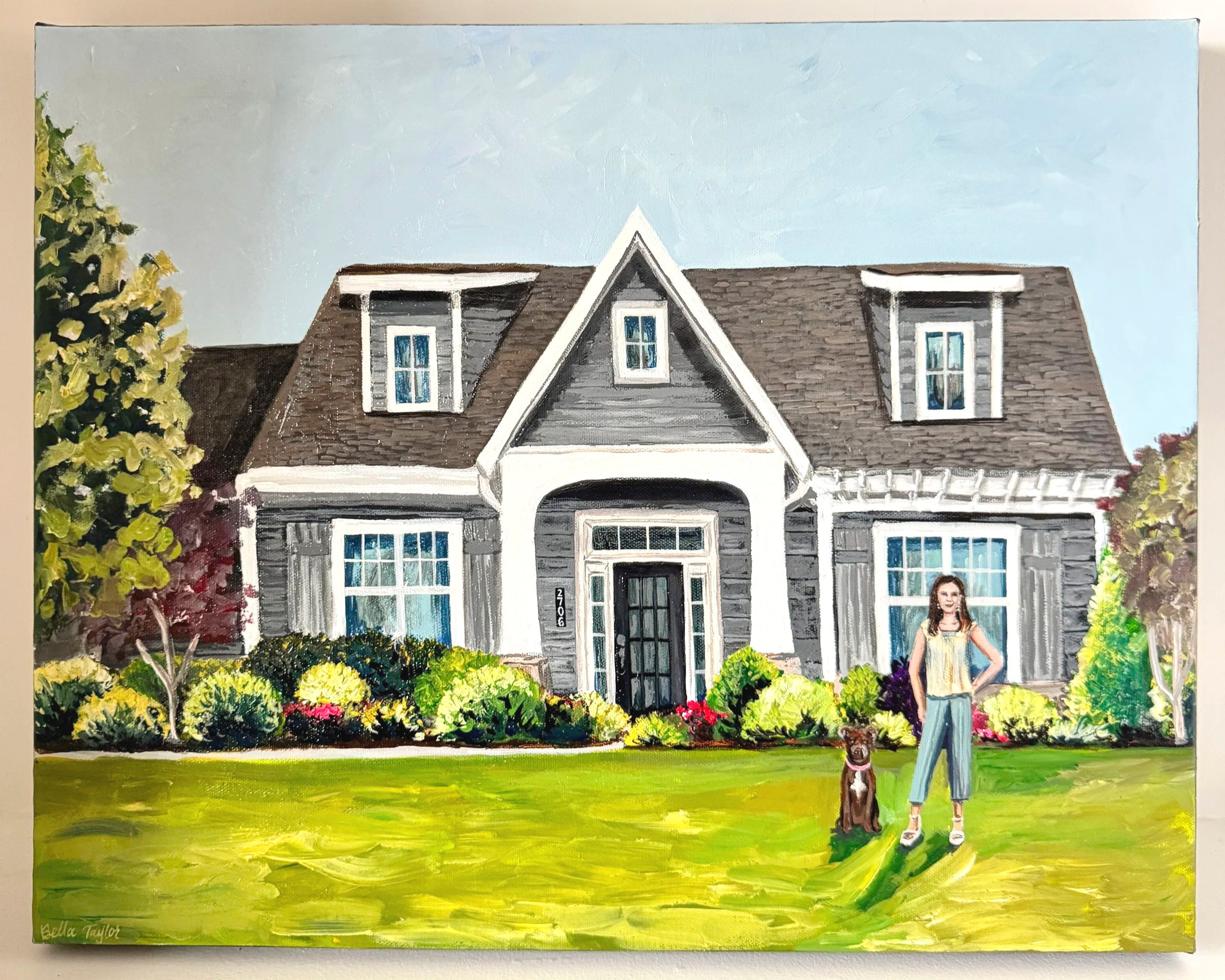 Painting of a house with gray siding, brown roof, and a woman with a dog standing on a lawn with colorful bushes in front.