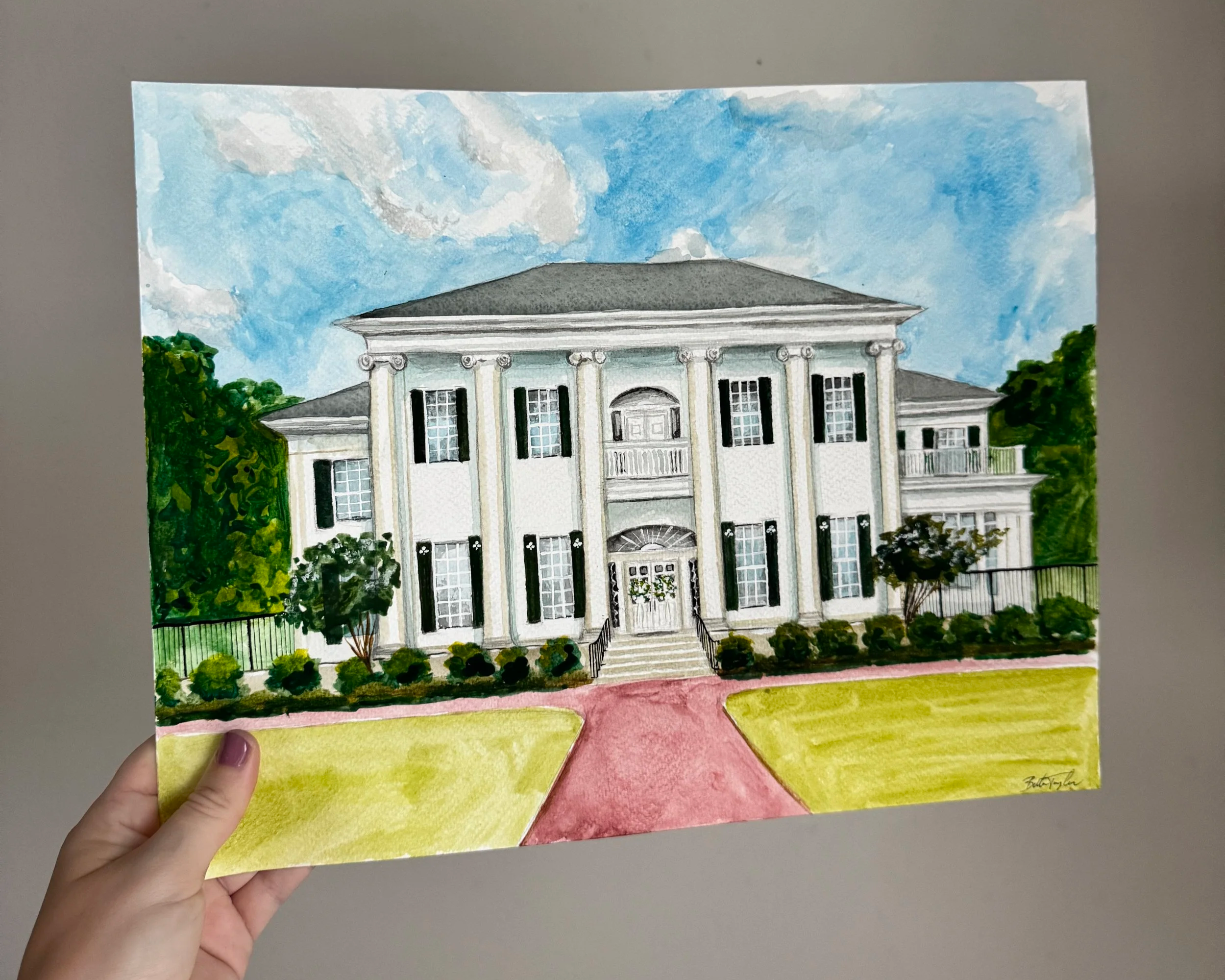 A watercolor painting of a large, white, two-story house with black shutters, surrounded by green trees and bushes. The house has a central balcony and steps leading to the front door, with a blue sky and some clouds in the background.