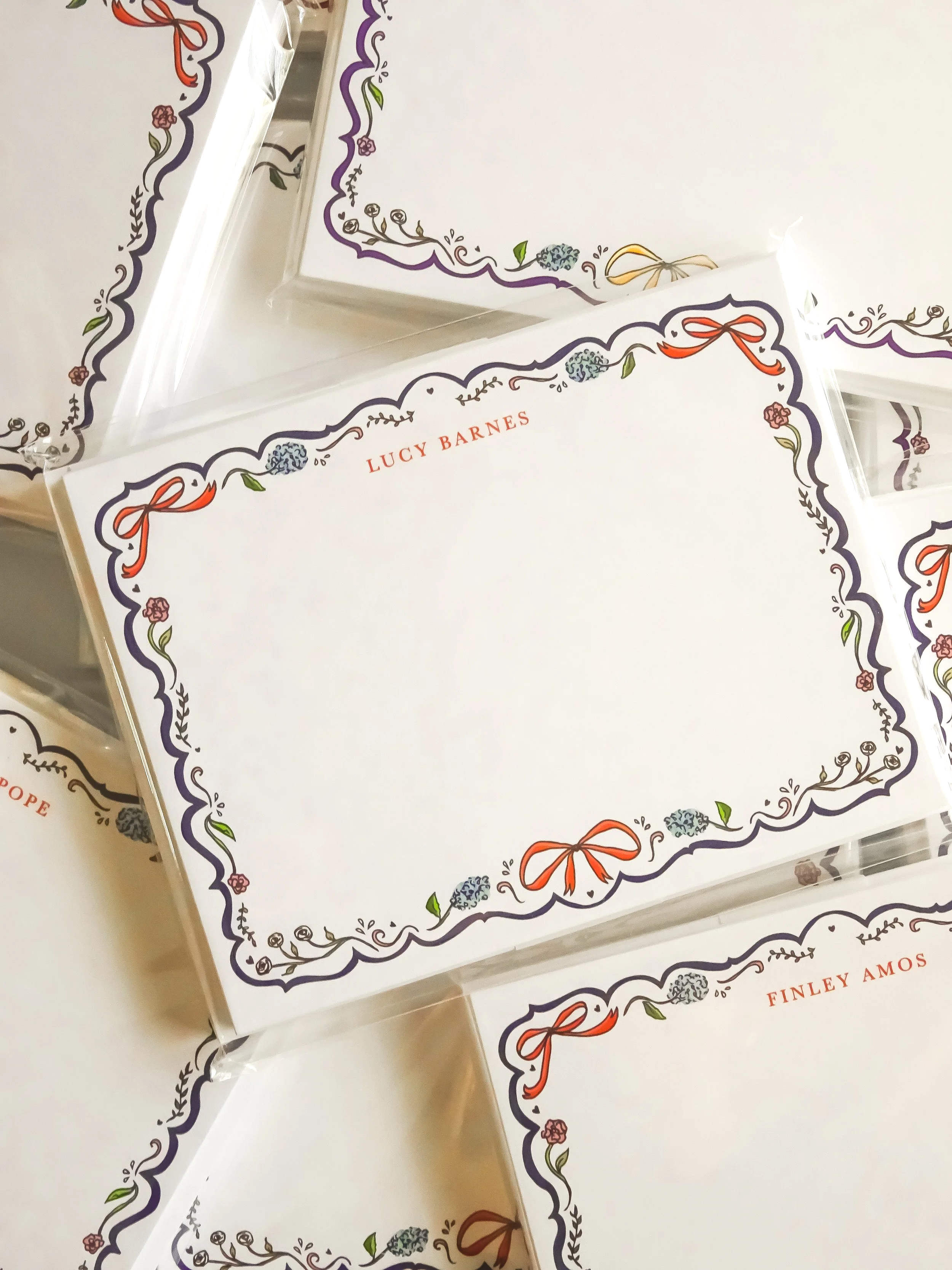Multiple sealed stationery sets with decorative floral borders. 