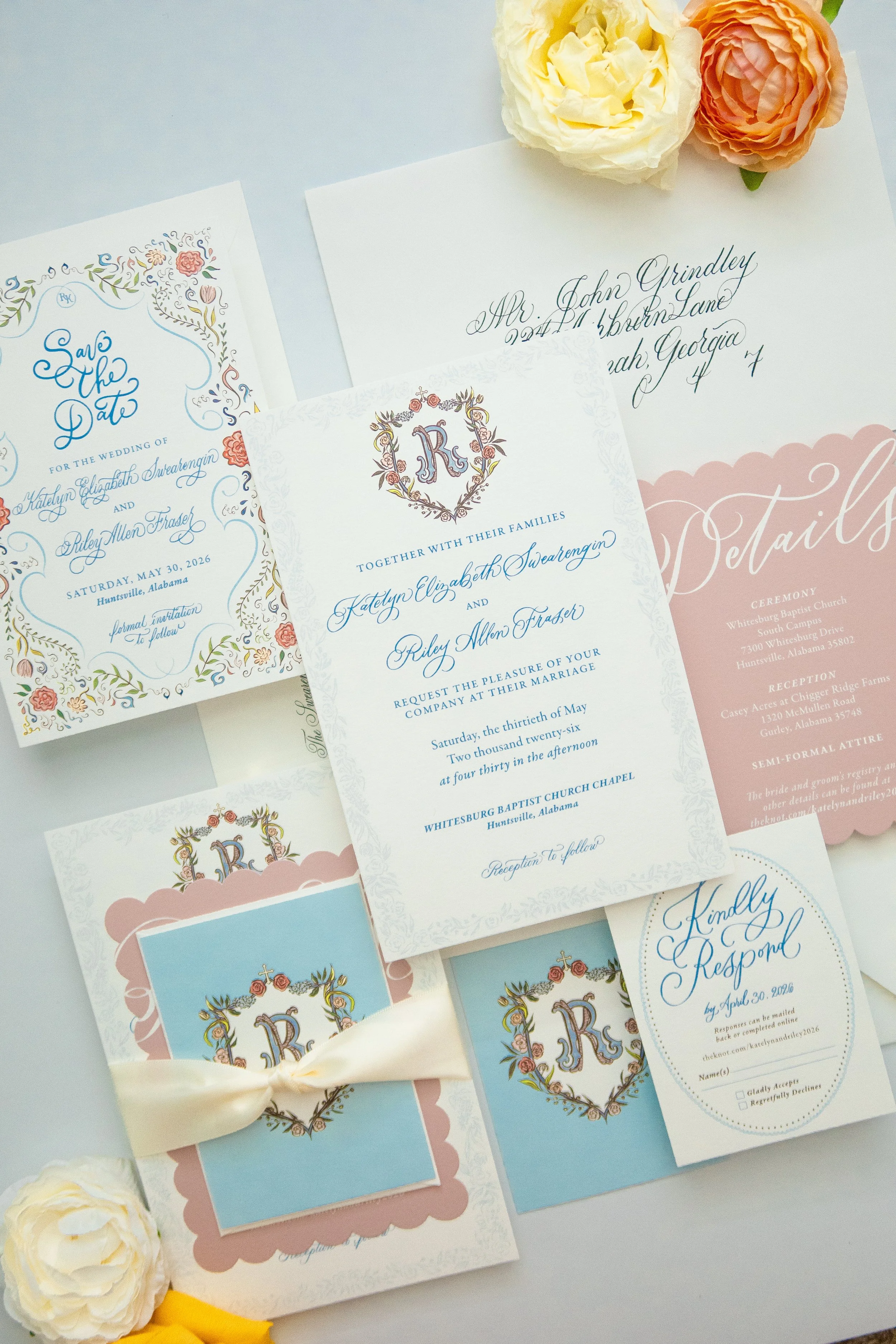 Collection of wedding invitation cards with floral and ornate designs, along with some cream-colored flowers and a ribbon.