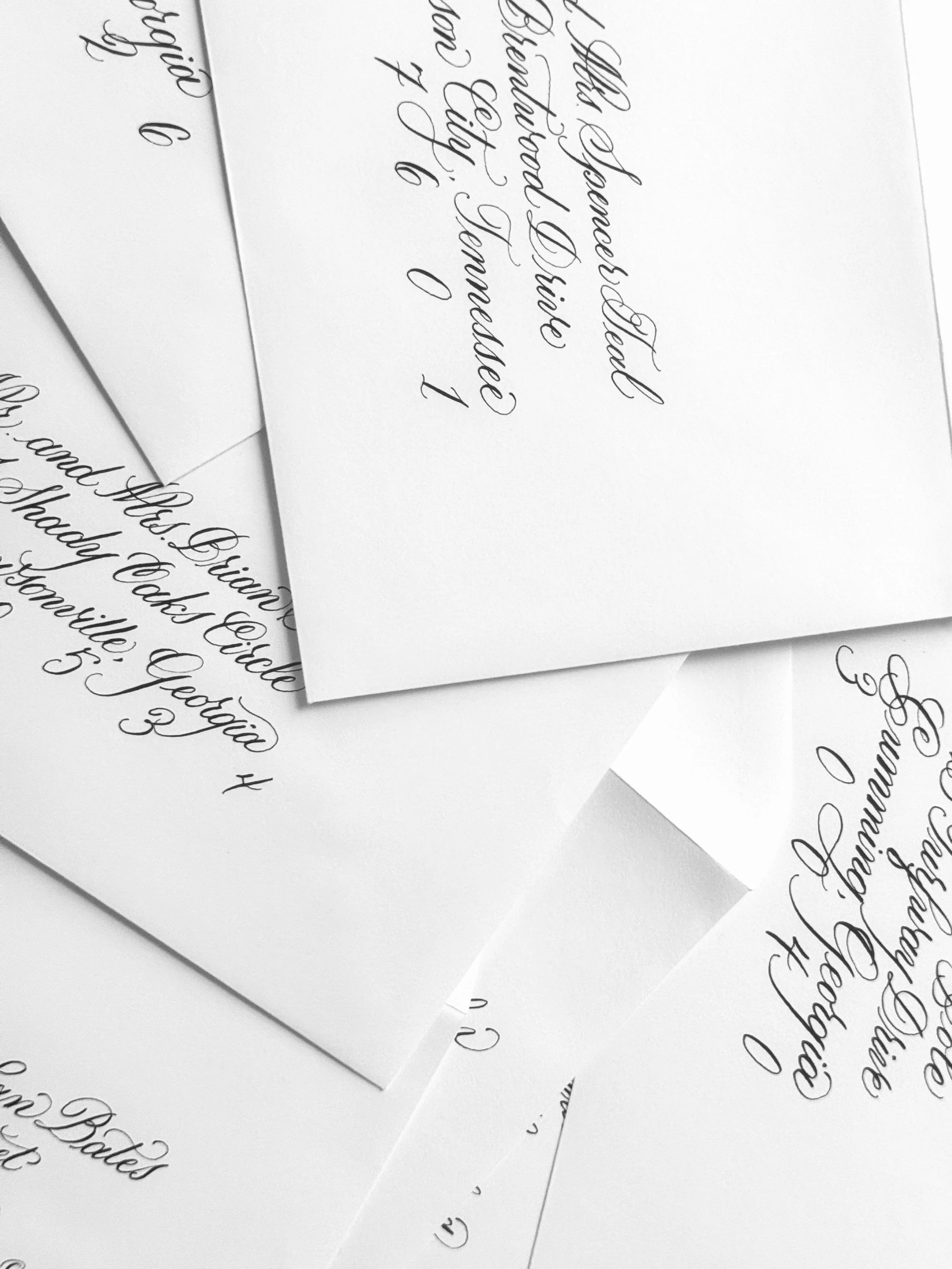 Several pieces of white paper with handwritten calligraphy text in black ink. 