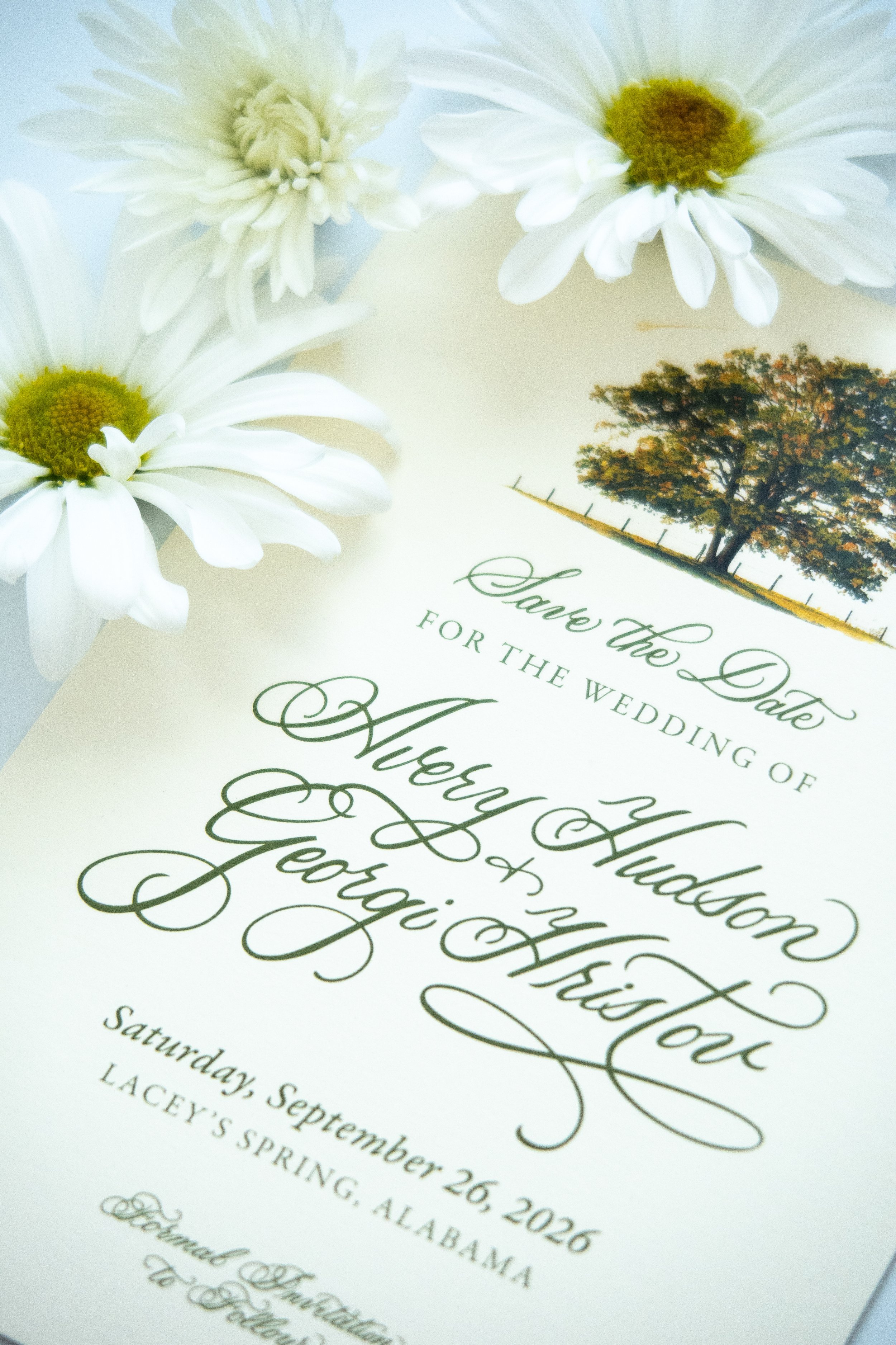 A wedding invitation with white daisies and a tree illustration, featuring elegant script text.